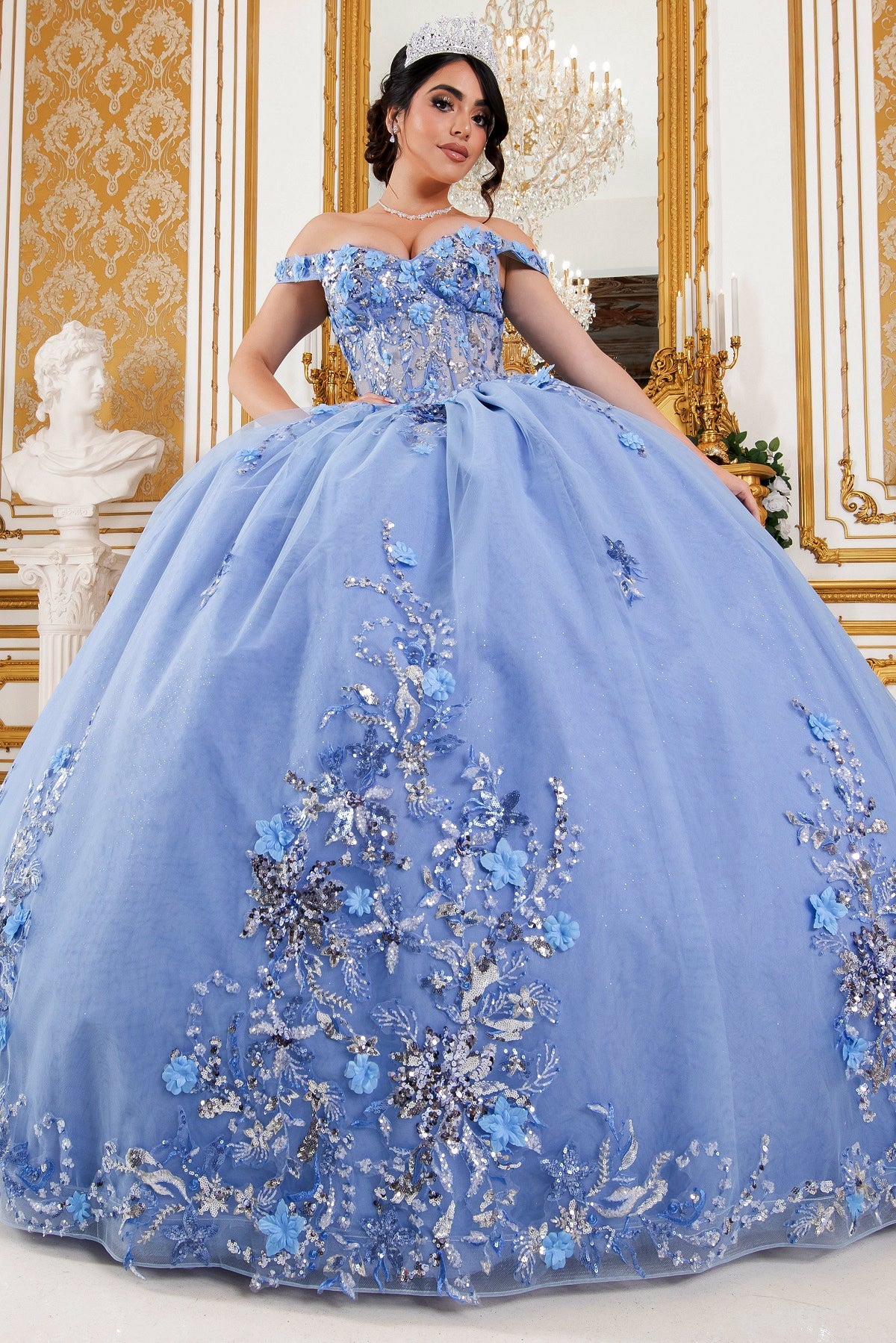 Front view of a woman wearing blue quinceanera ball gown with seven-layer tulle skirt, floral beaded appliques, and lace-up corset