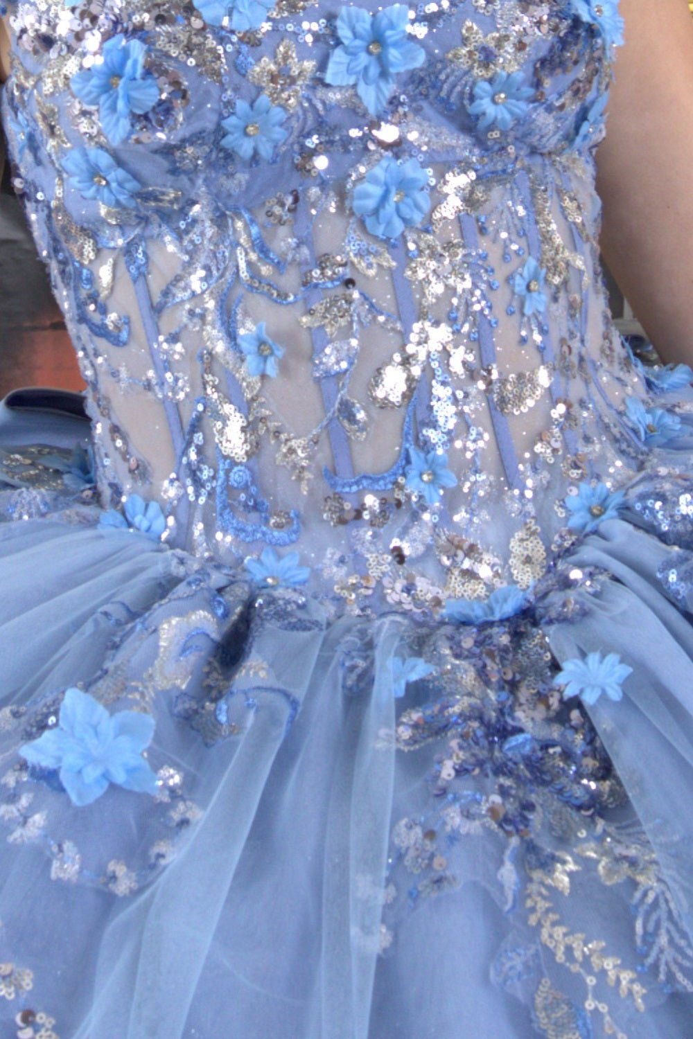 Detailed close-up of a woman wearing blue quinceanera ball gown with seven-layer tulle skirt, floral beaded appliques, and embroidered bodice