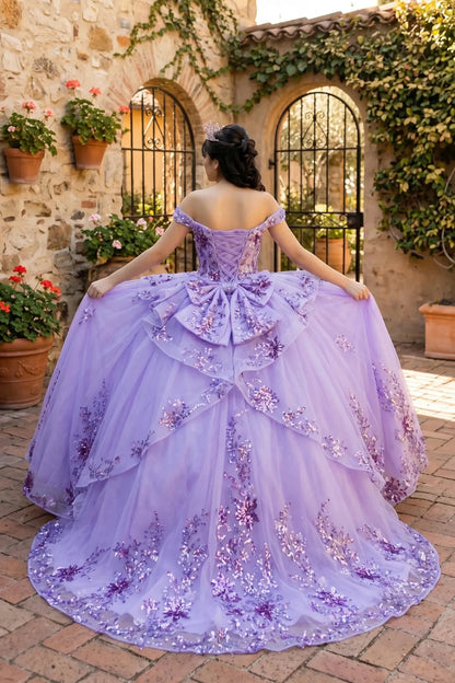 Back view of a woman wearing lilac quinceanera ball gown with seven-layer tulle skirt, floral beaded appliques, and lace-up train