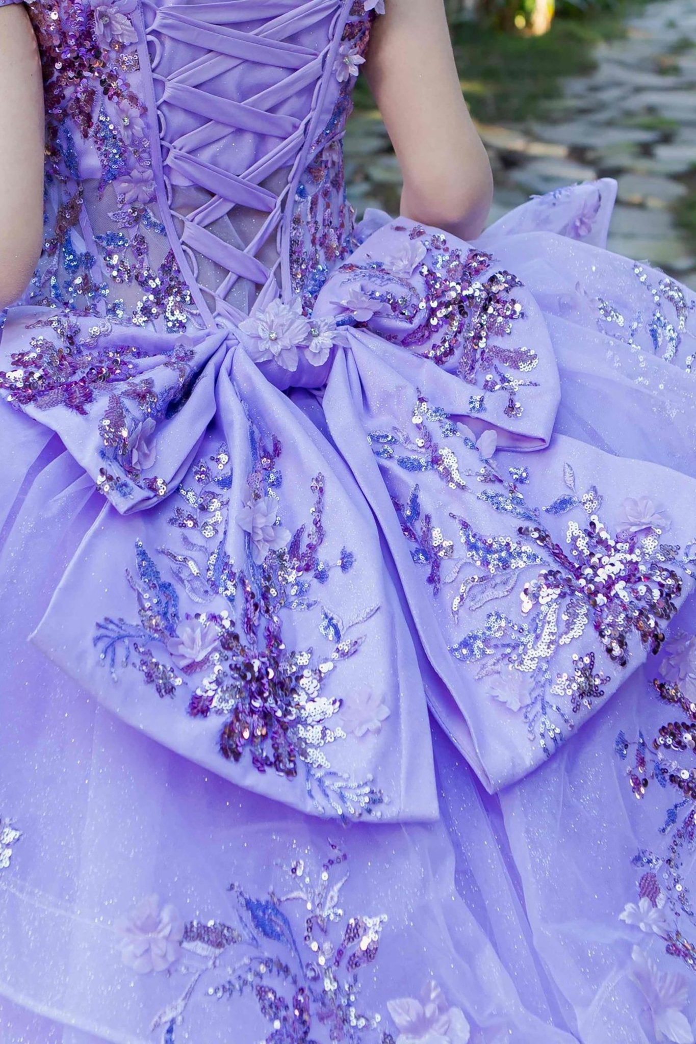 Close-up of a woman wearing lilac quinceanera ball gown ribbon with floral beaded appliques and seven-layer tulle skirt