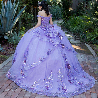 Back view of a woman wearing lilac quinceanera ball gown with seven-layer tulle skirt, floral beaded appliques, and lace-up train