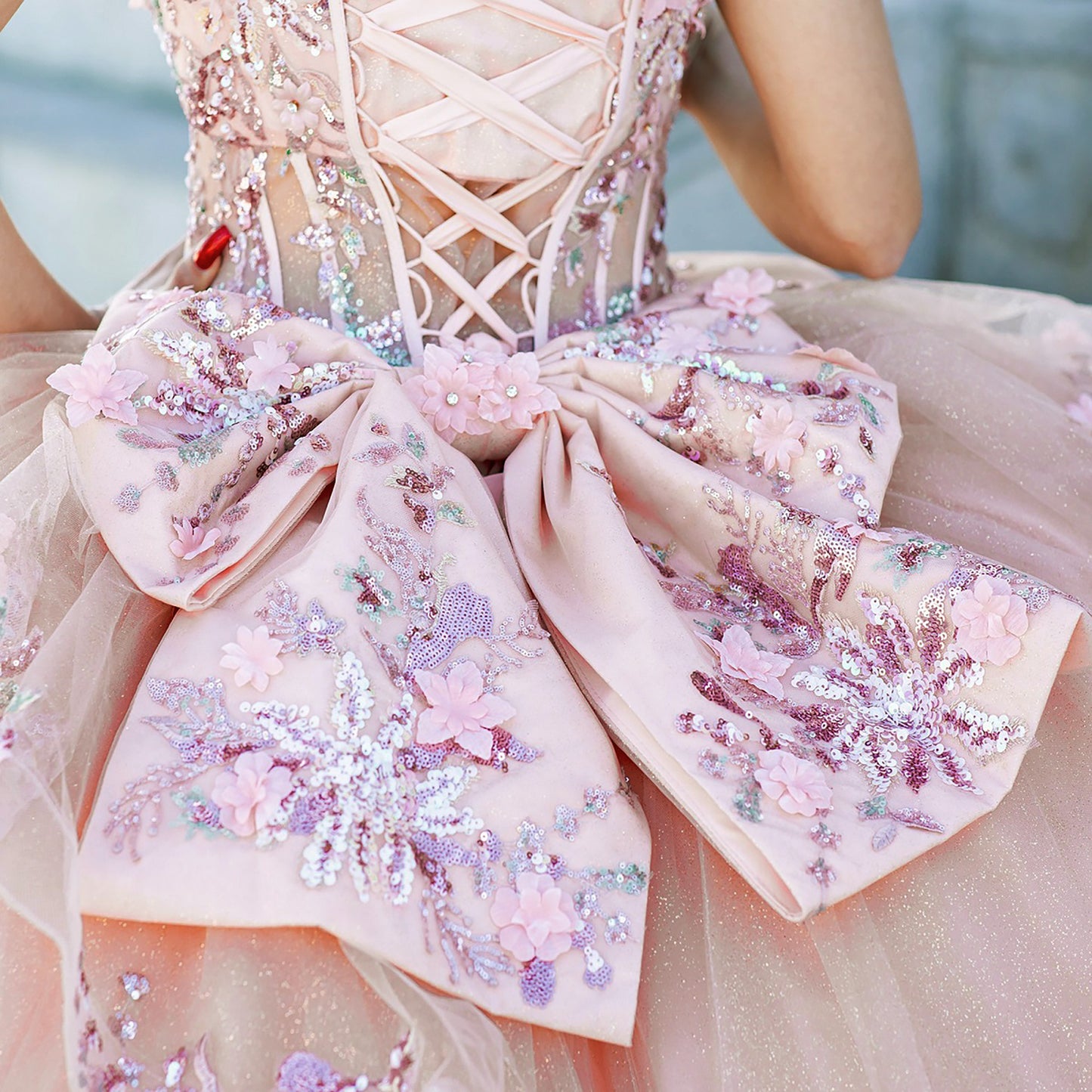 Close-up of a woman wearing peach blush quinceanera dress bodice with floral embroidery, sequins, and beaded appliques