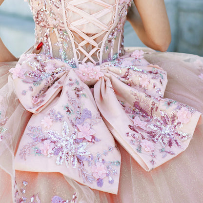 Close-up of a woman wearing peach blush quinceanera dress bodice with floral embroidery, sequins, and beaded appliques