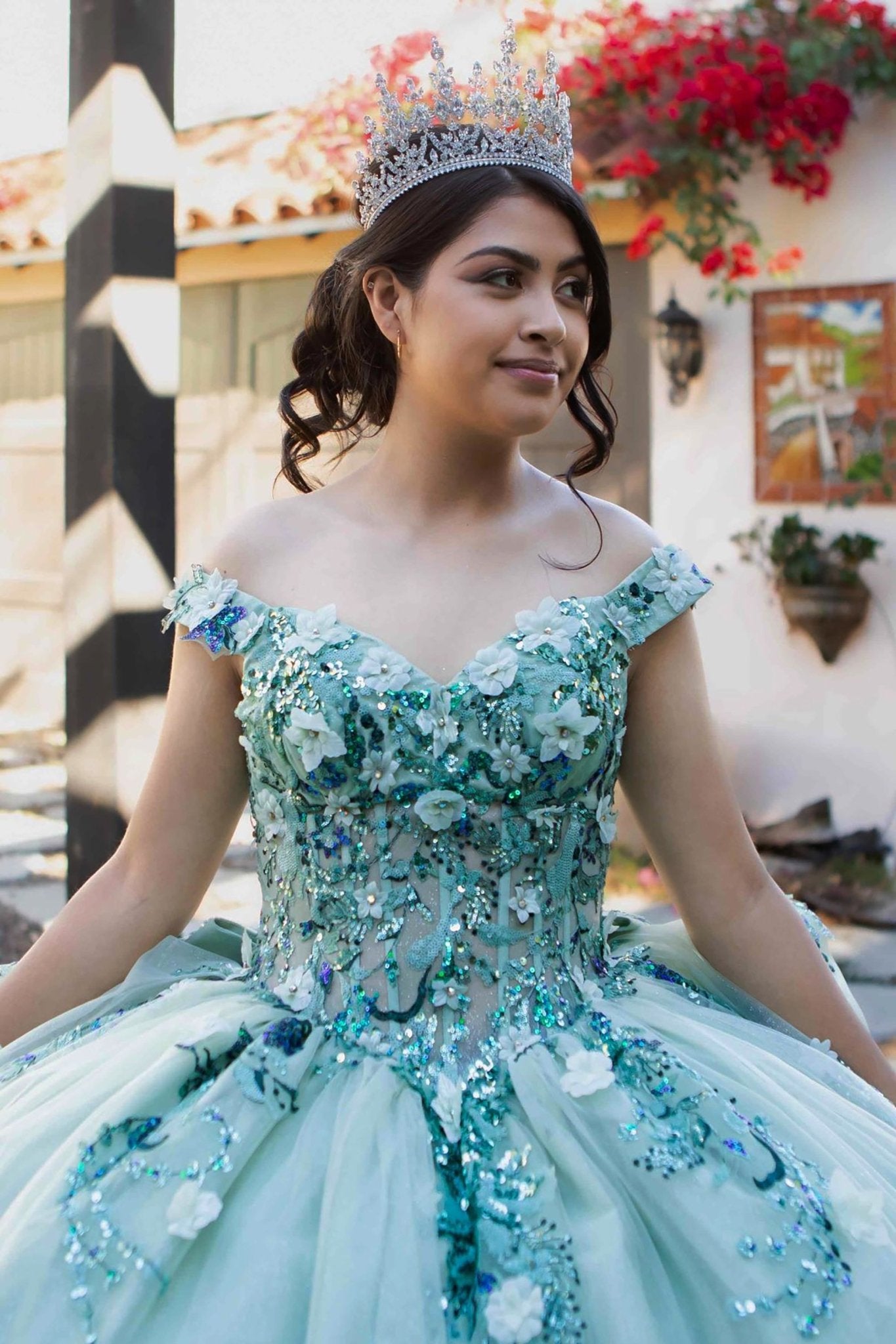Front zoom view of a woman wearing sage quinceanera ball gown with off-shoulder neckline, floral beaded appliques, and layered tulle skirt