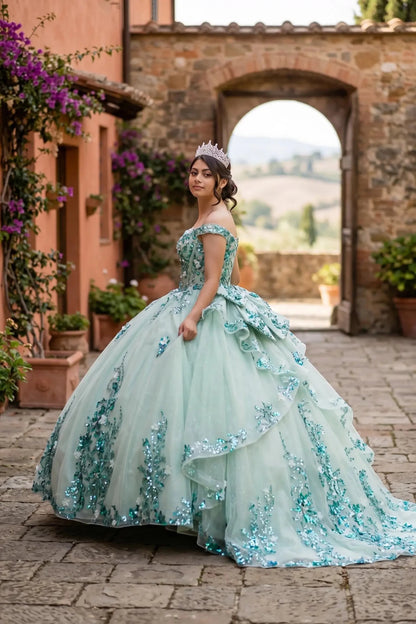Side view of a woman wearing sage quinceanera ball gown with off-shoulder neckline, floral beaded appliques, and layered tulle skirt