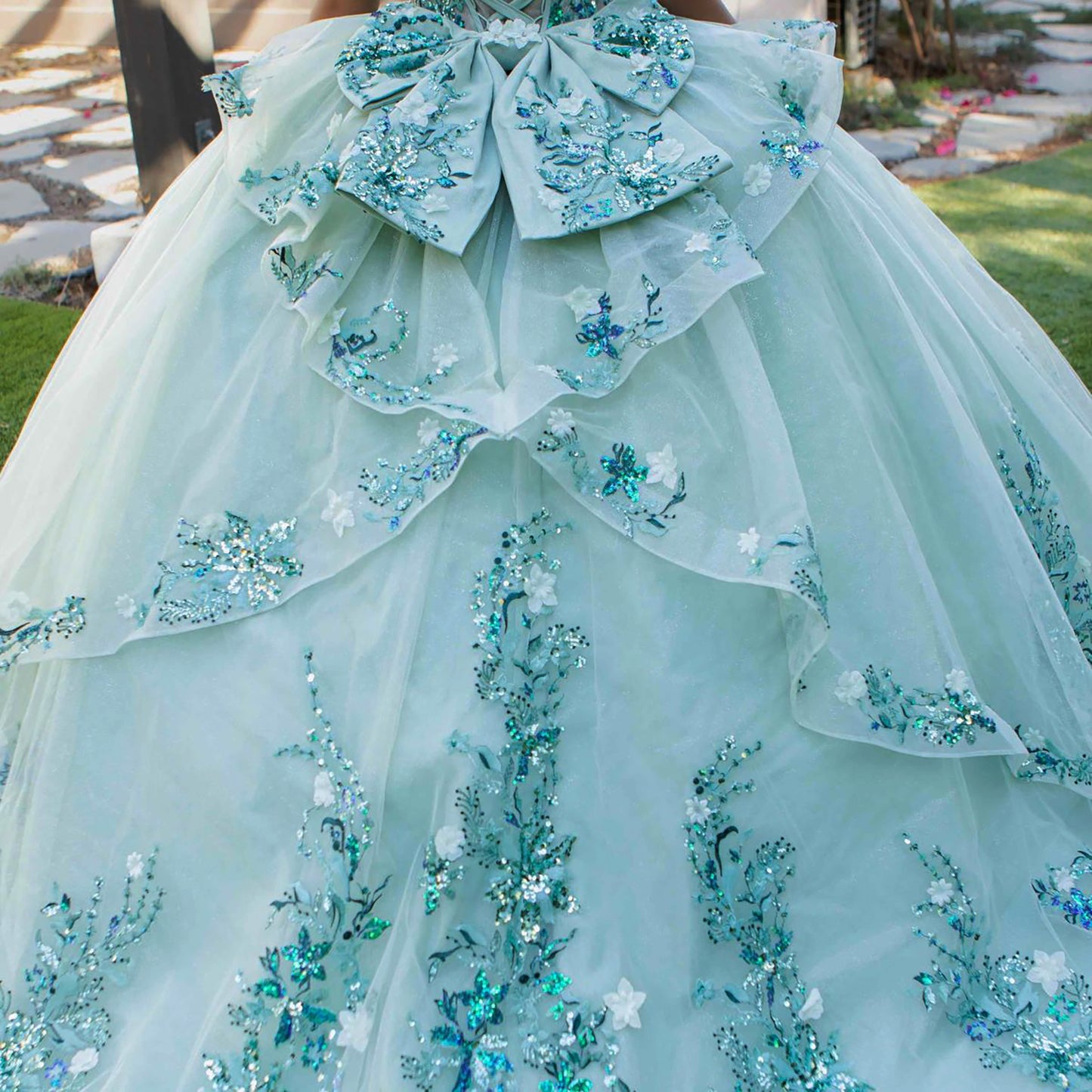 Close-up of sage quinceanera ball gown tulle fabric with floral beaded appliques and layered detailing