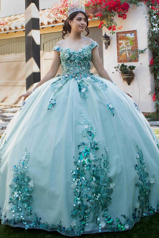 A girl wearing a sage quince ballgown with a sweetheart neckline, off-shoulder design, and a floral and beaded appliqué bodice, standing outdoors. 