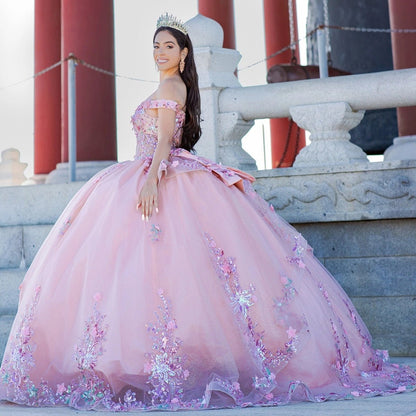 Displayed in a angled view, the Peach Blush quinceañera dress has off-shoulder neckline, floral skirt border and back bow.