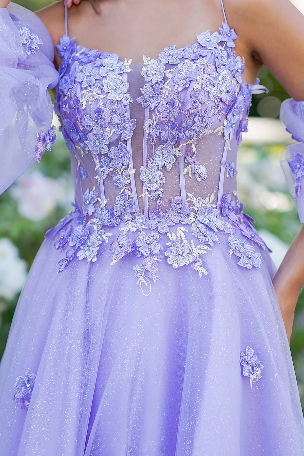 Close-up view reveals lilac prom dress featuring corset bodice with 3D floral appliques.