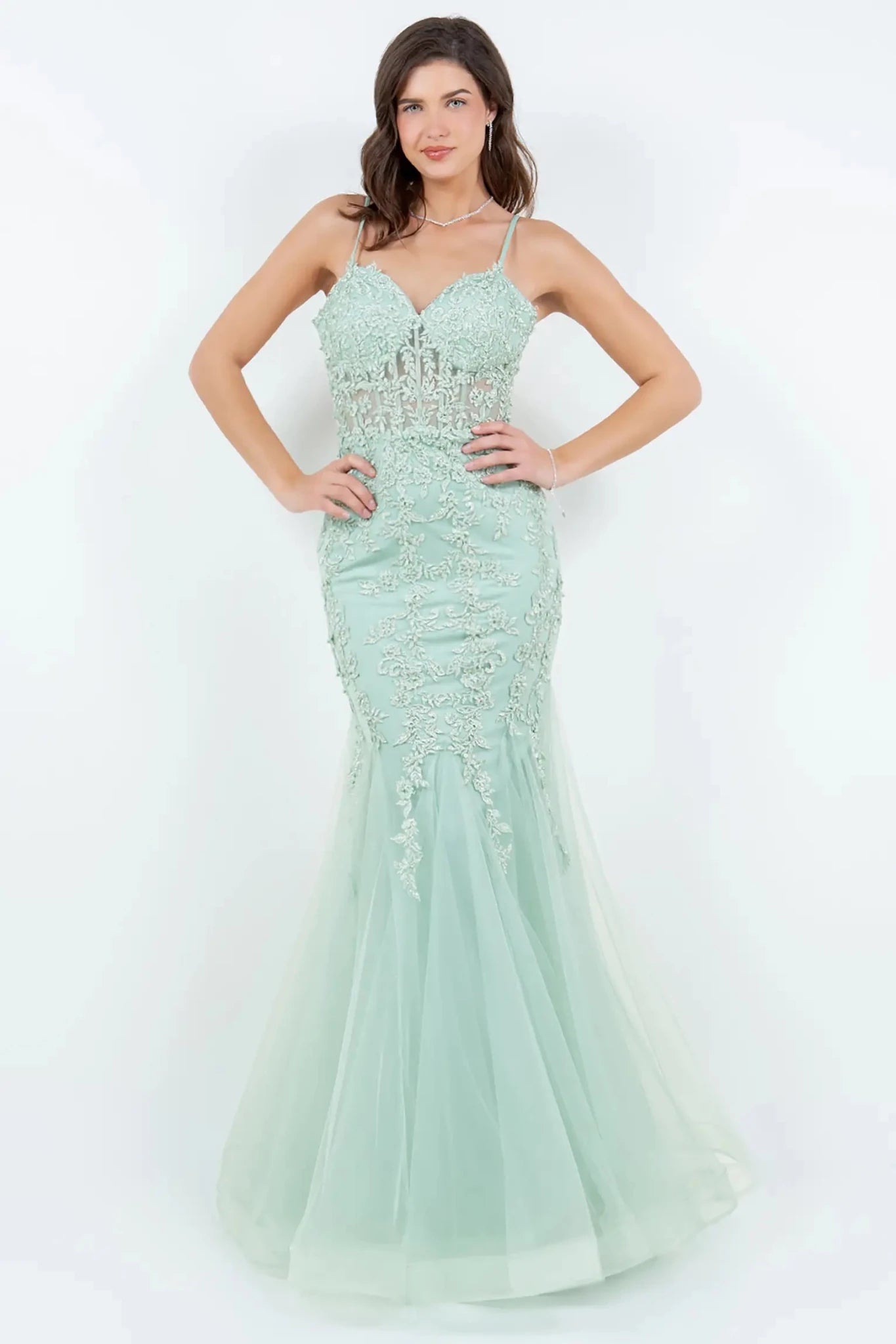 A full-length view of a woman wearing sage mermaid dress with lace-up corset closure.