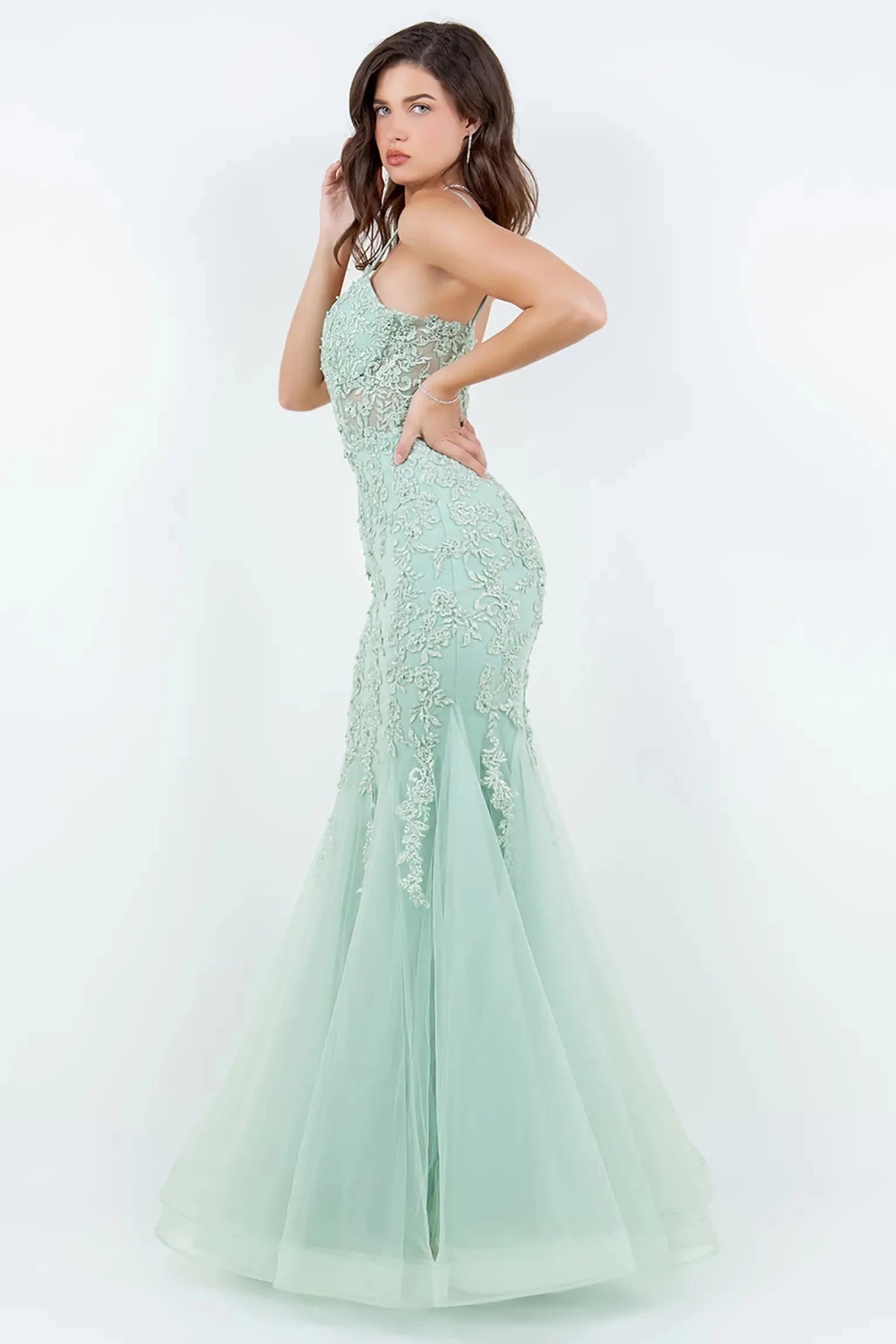 A side profile view of a woman wearing a sage mermaid prom dress, highlighting the sculpted silhouette and dramatic flare.
