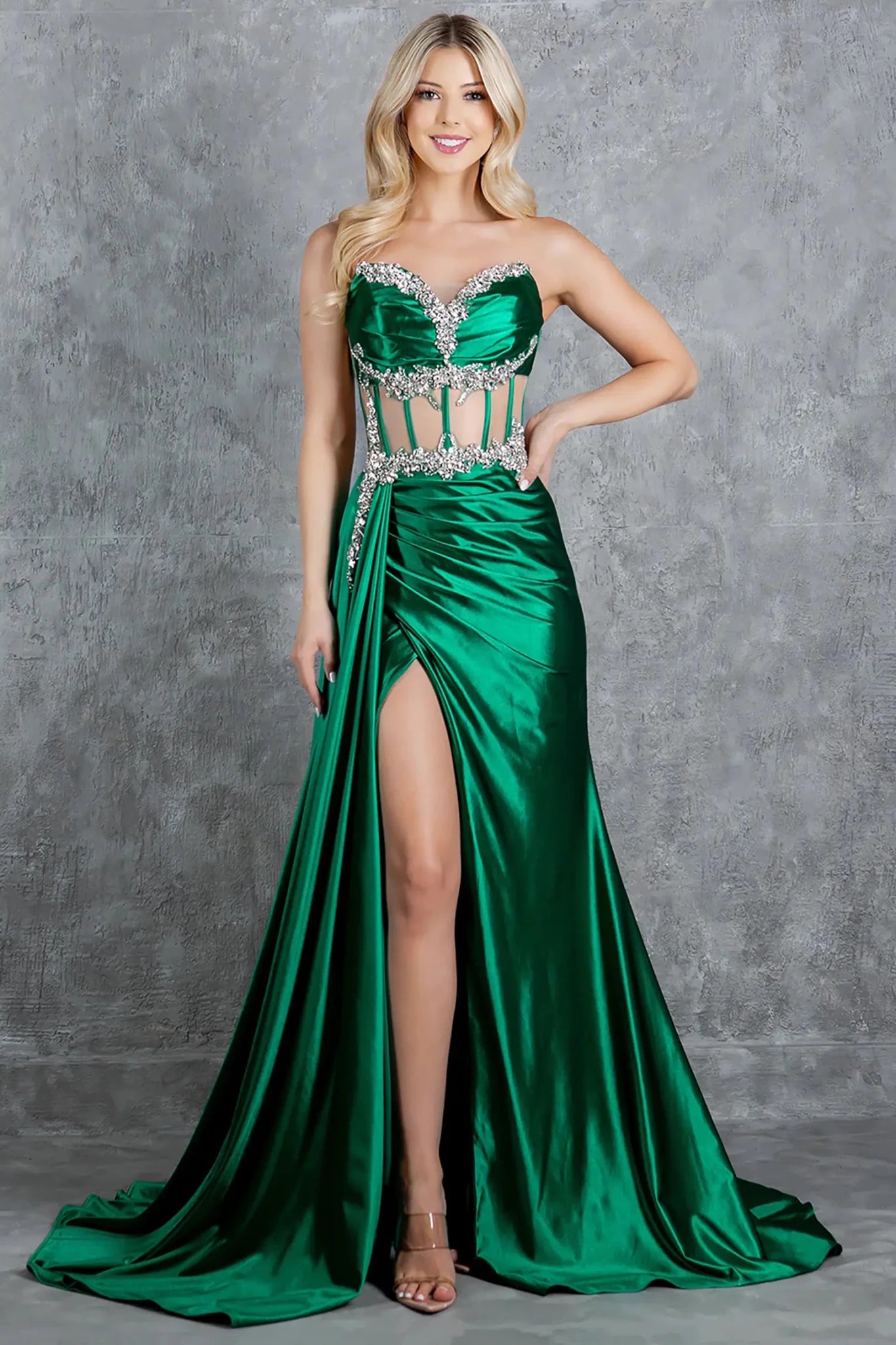 Full front view of a women wearing green satin corset prom dress with crystal embellished bodice and slit.