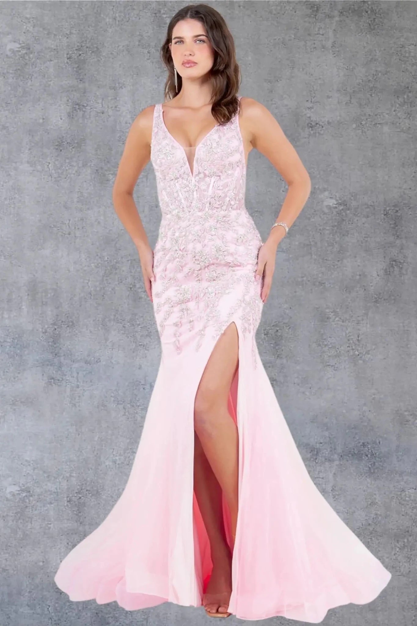Full front view of a women wearing pink sleeveless prom dress with chantilly lace bodice and slit.