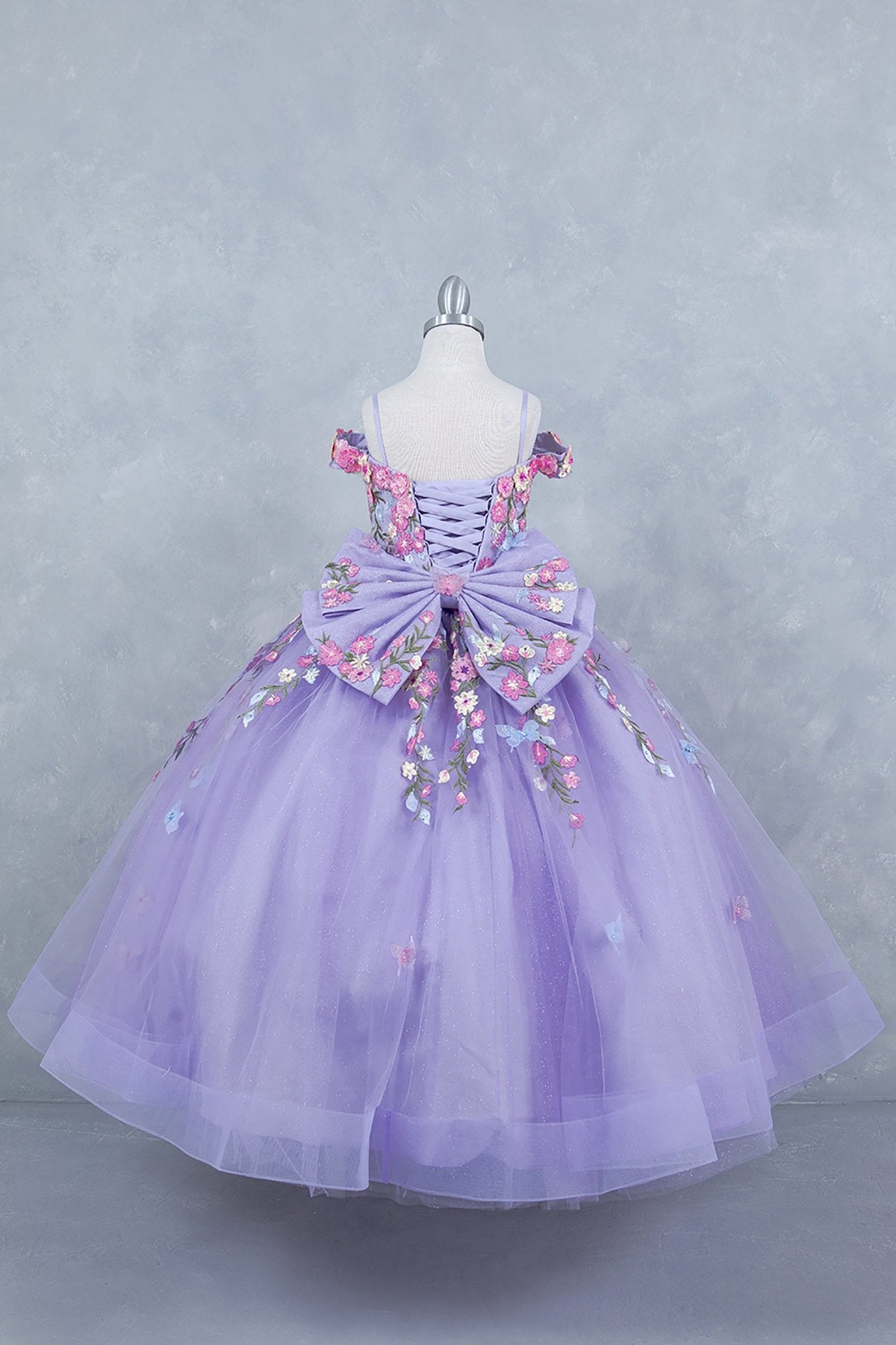 Lilac back view kids mini quinceañera mini quince dress with multicolor daisy embroidery and large detachable bow.