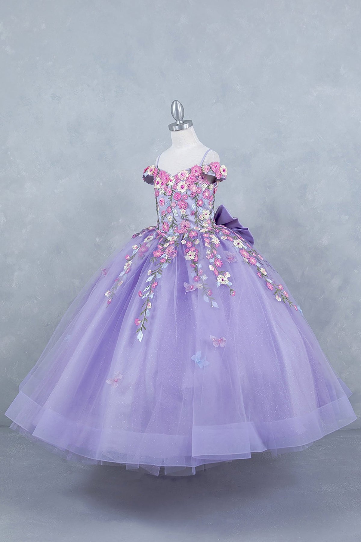 Lilac side view kids mini quinceañera mini quince dress with multicolor daisy embroidery and large detachable bow.