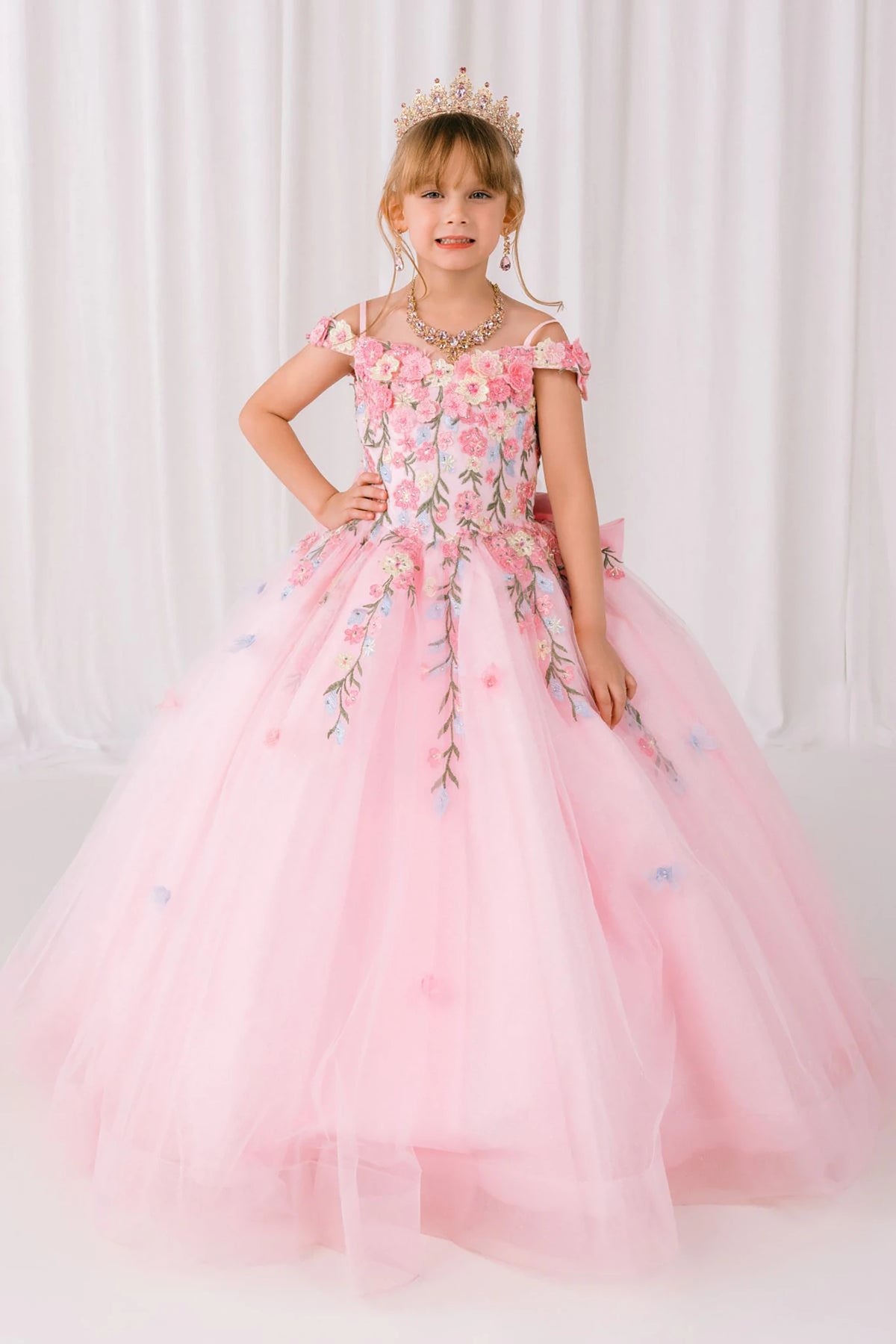 Pink front view kids mini quinceañera mini quince dress with multicolor daisy embroidery and large detachable bow.