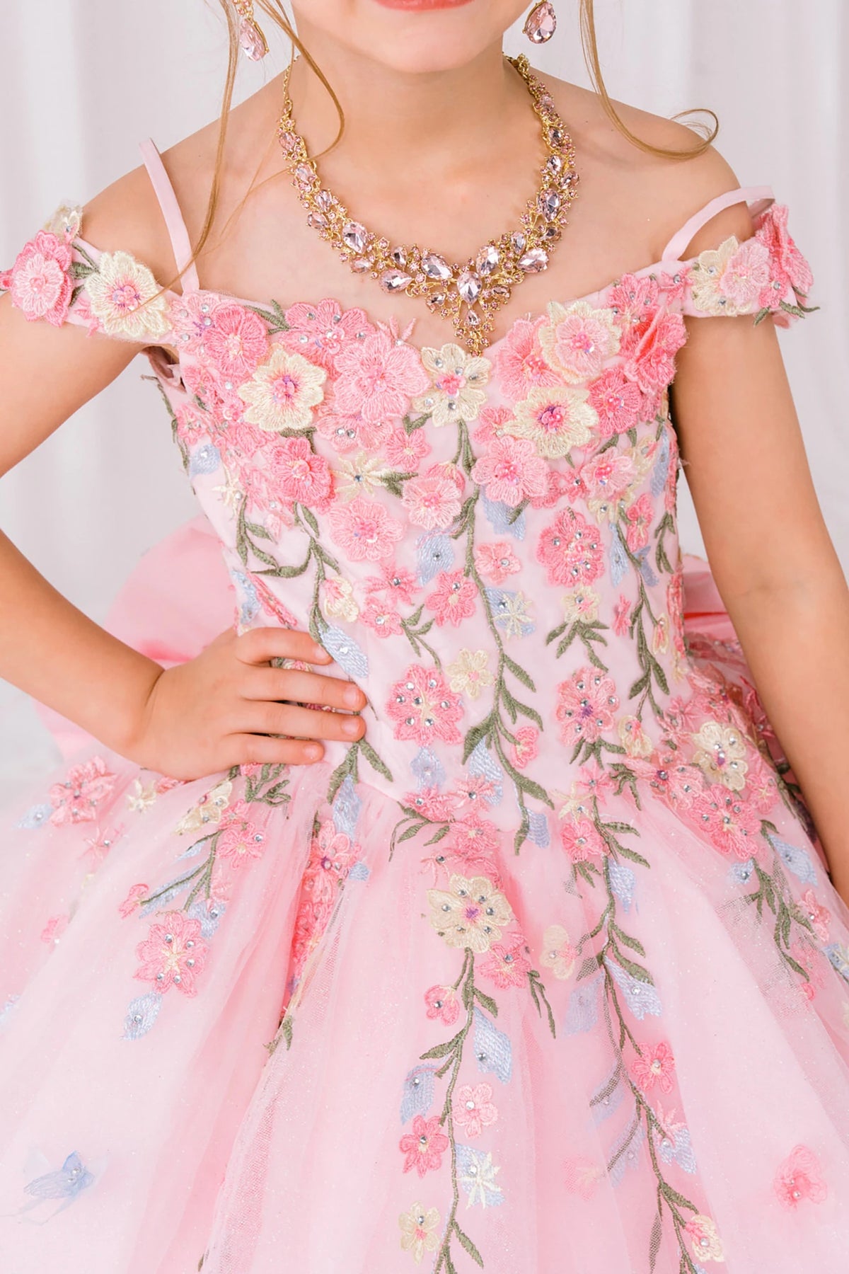 Pink back zoom kids mini quinceañera mini quince dress with multicolor daisy embroidery and large detachable bow.
