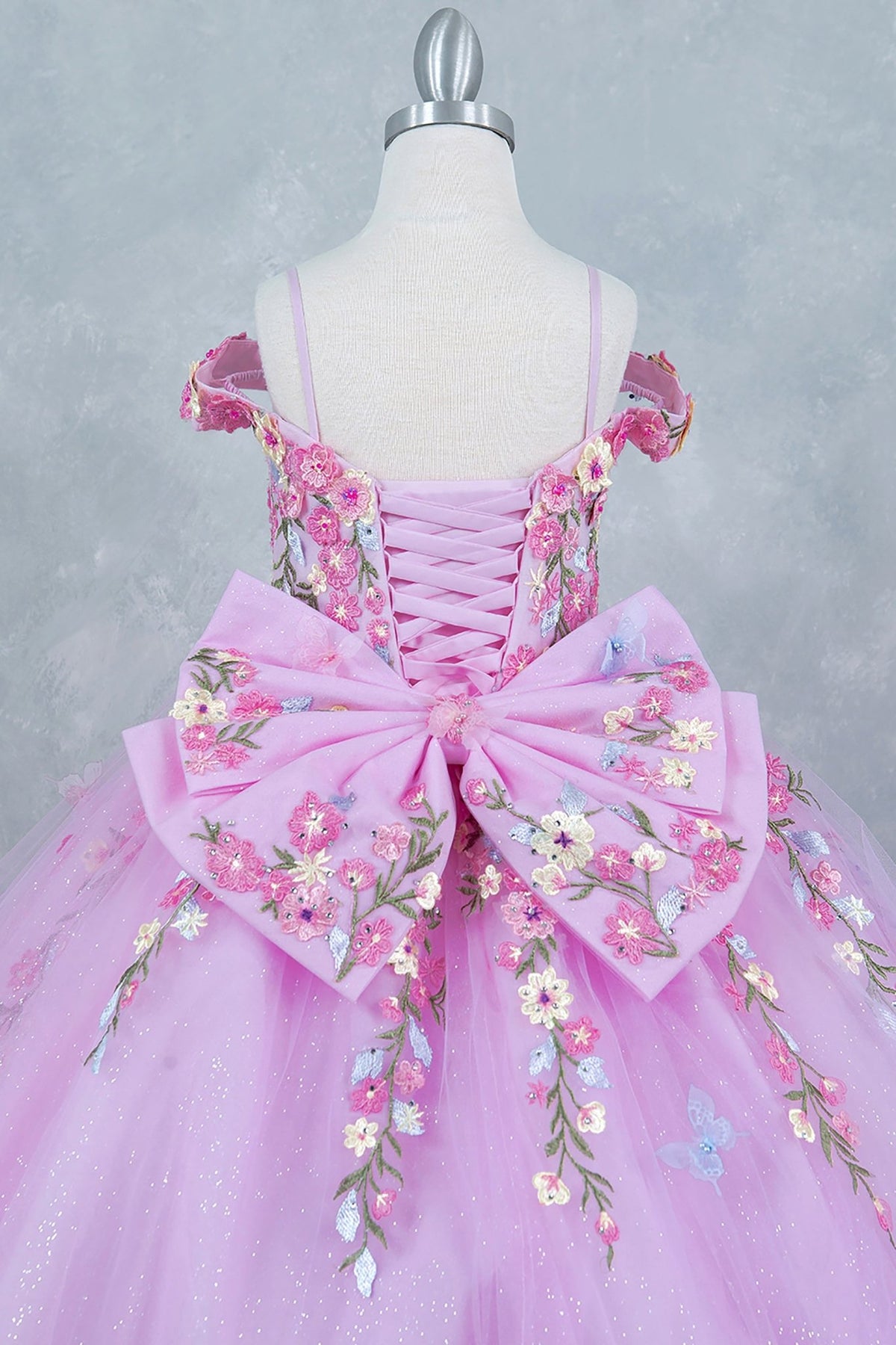 Pink back zoom kids mini quinceañera mini quince dress with multicolor daisy embroidery and large detachable bow.