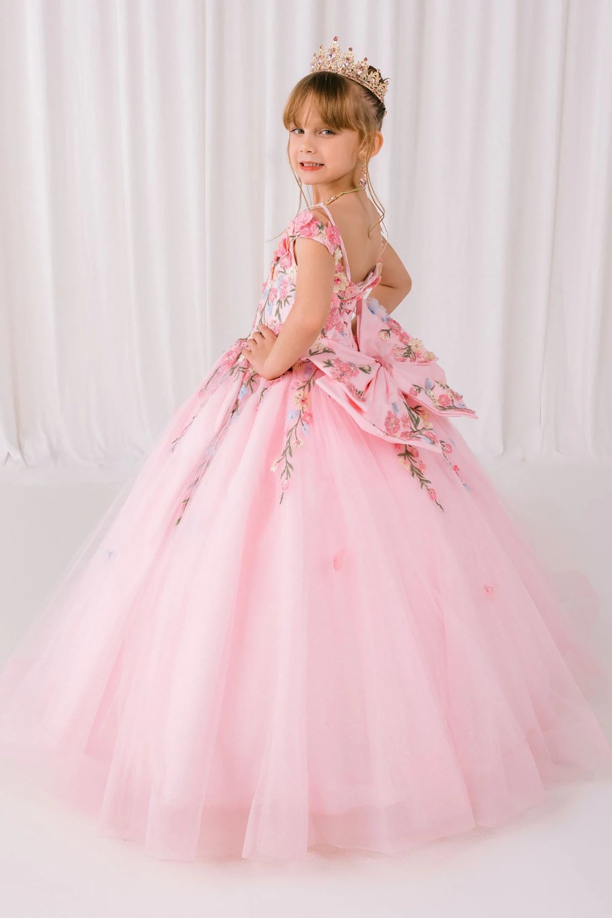 Pink front view kids mini quinceañera mini quince dress with floral lace and detachable bow detail.
