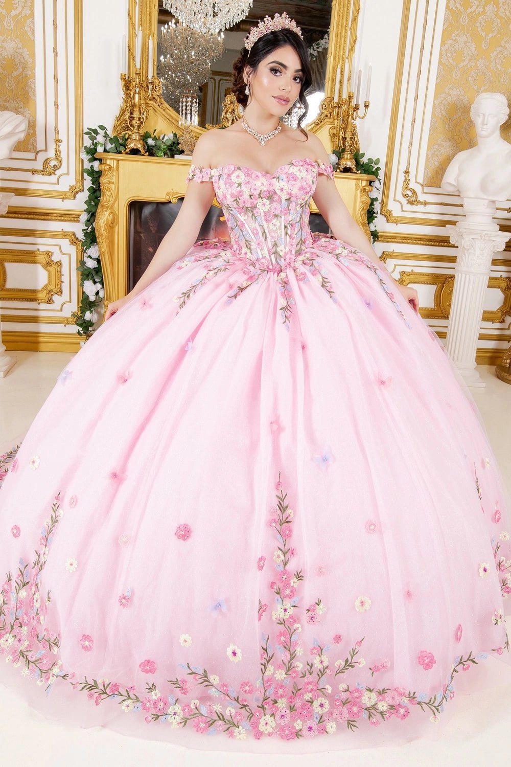 Shown in a full-skirt front view, the Pink quinceañera dress has off-shoulder floral bodice and floral applique border on the ball skirt.