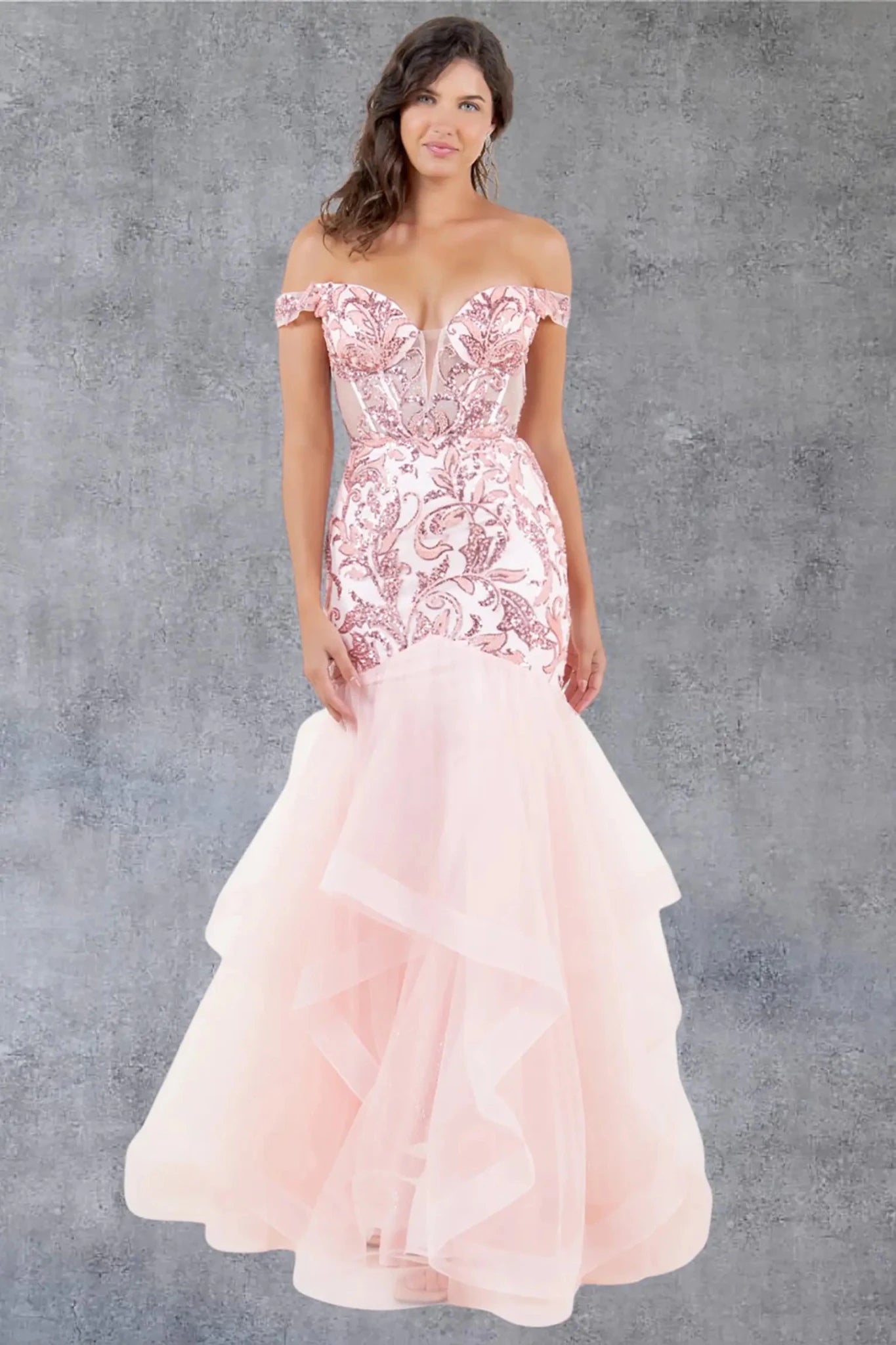 A full-length view of a woman wearing blush formal dress with a lace-up corset and layered mermaid tulle skirt.