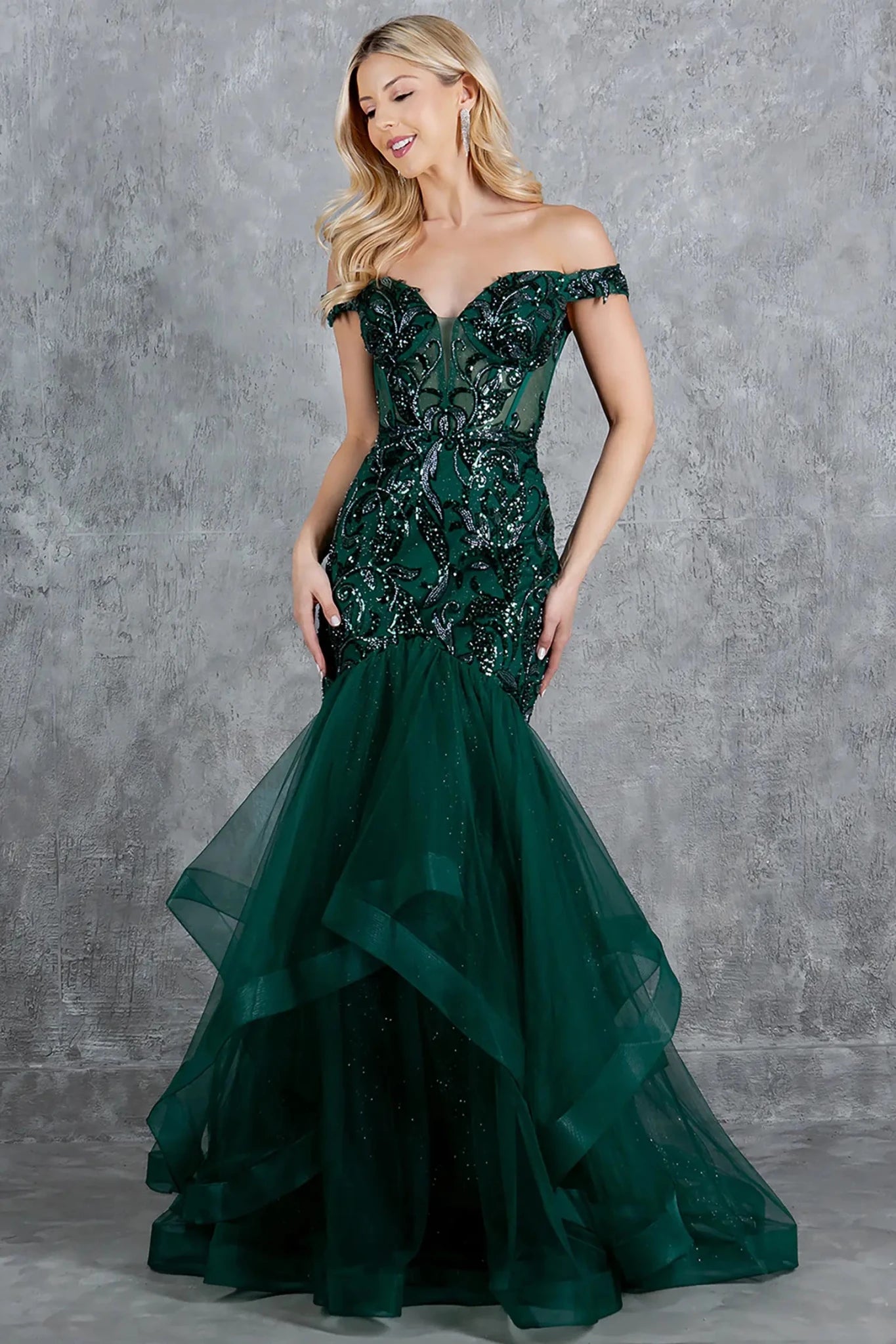 A full-length view of a woman wearing green formal prom dress with a lace-up corset and voluminous tulle skirt.