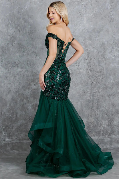 A full back view of a woman wearing a green formal dress featuring a lace-up corset and voluminous tulle skirt.