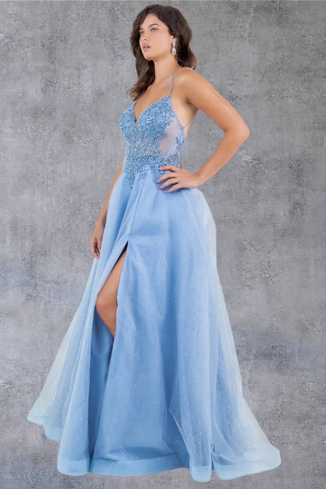 A side profile view of a woman wearing a blue A-line prom dress, emphasizing the flowing silhouette.