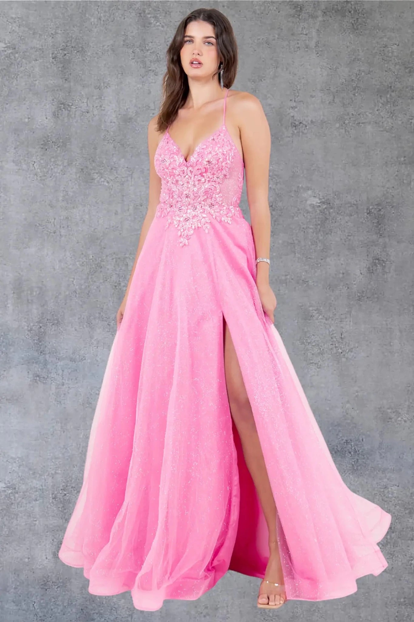 A full-length view of a woman wearing pink formal prom dress with an open back and straps.