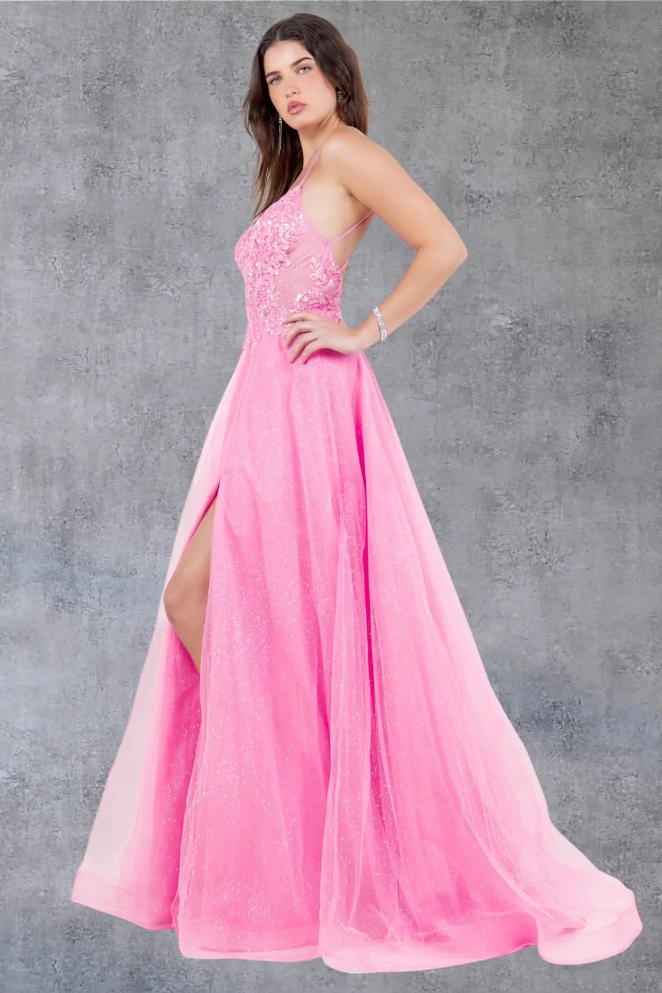 A side profile view of a woman wearing a pink prom dress, showcasing the flowing A-line silhouette.