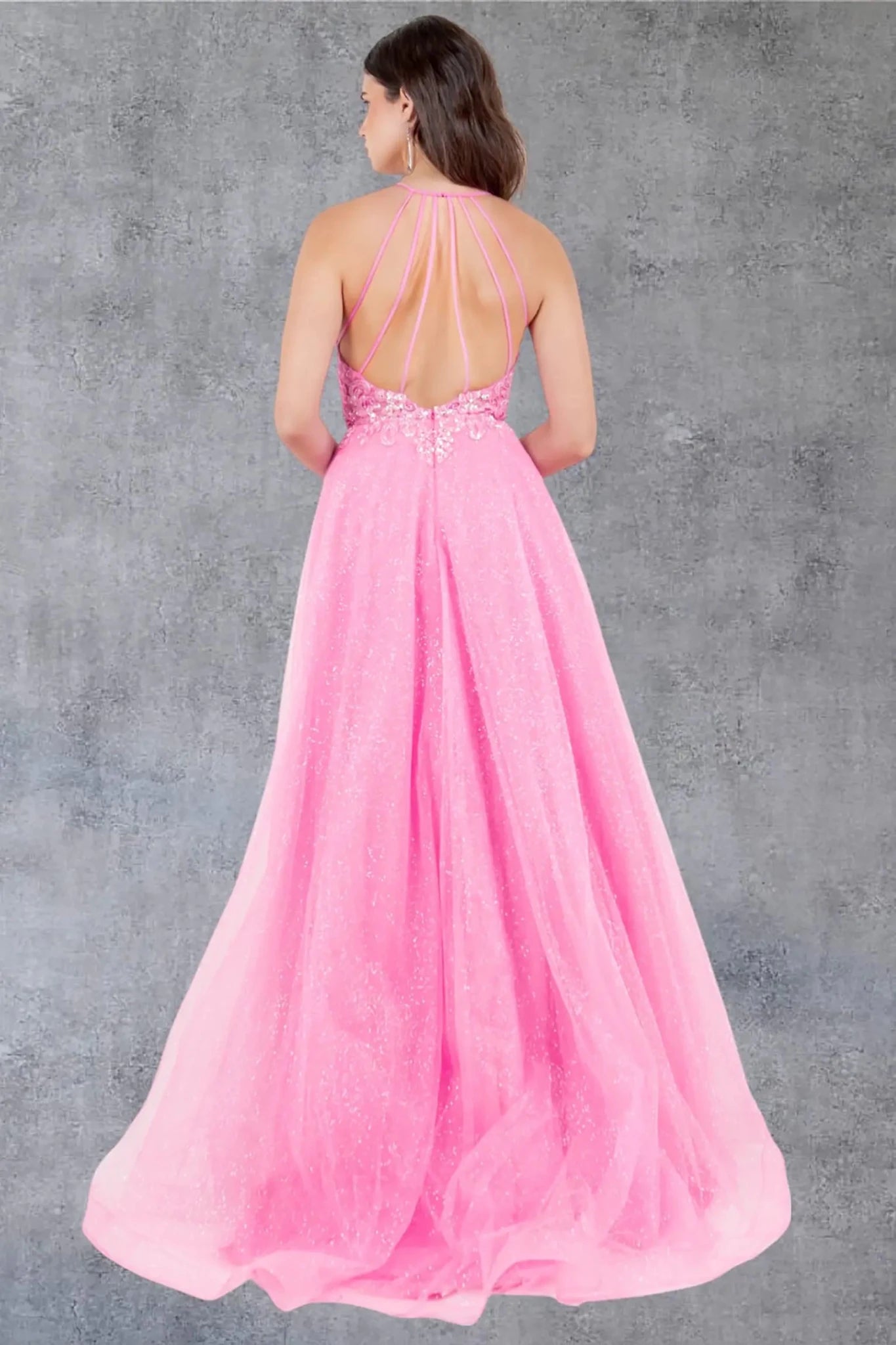 A full back view of a woman wearing a pink formal dress featuring an open back with straps.