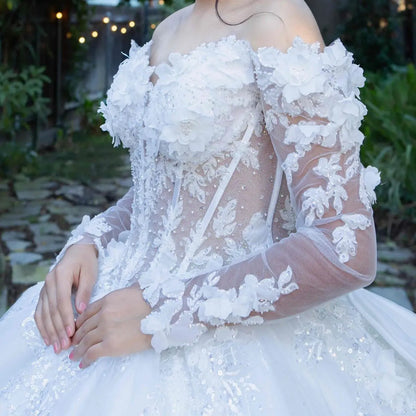 Side close-up of an off-white quinceanera dress showing lace appliques, beadwork bodice, sheer sleeve detail, and glitter tulle fabric