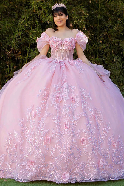 Woman in a pink floral dress standing outdoors with greenery in the background