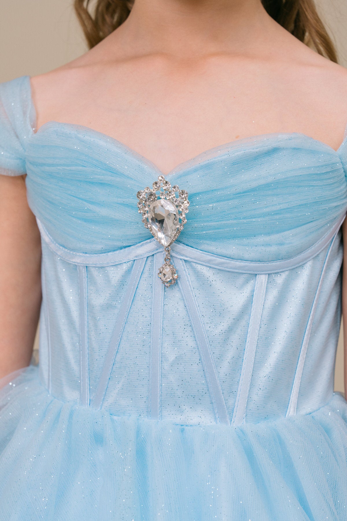 close up the top of sky blue flower girl dress and rhinestone center.