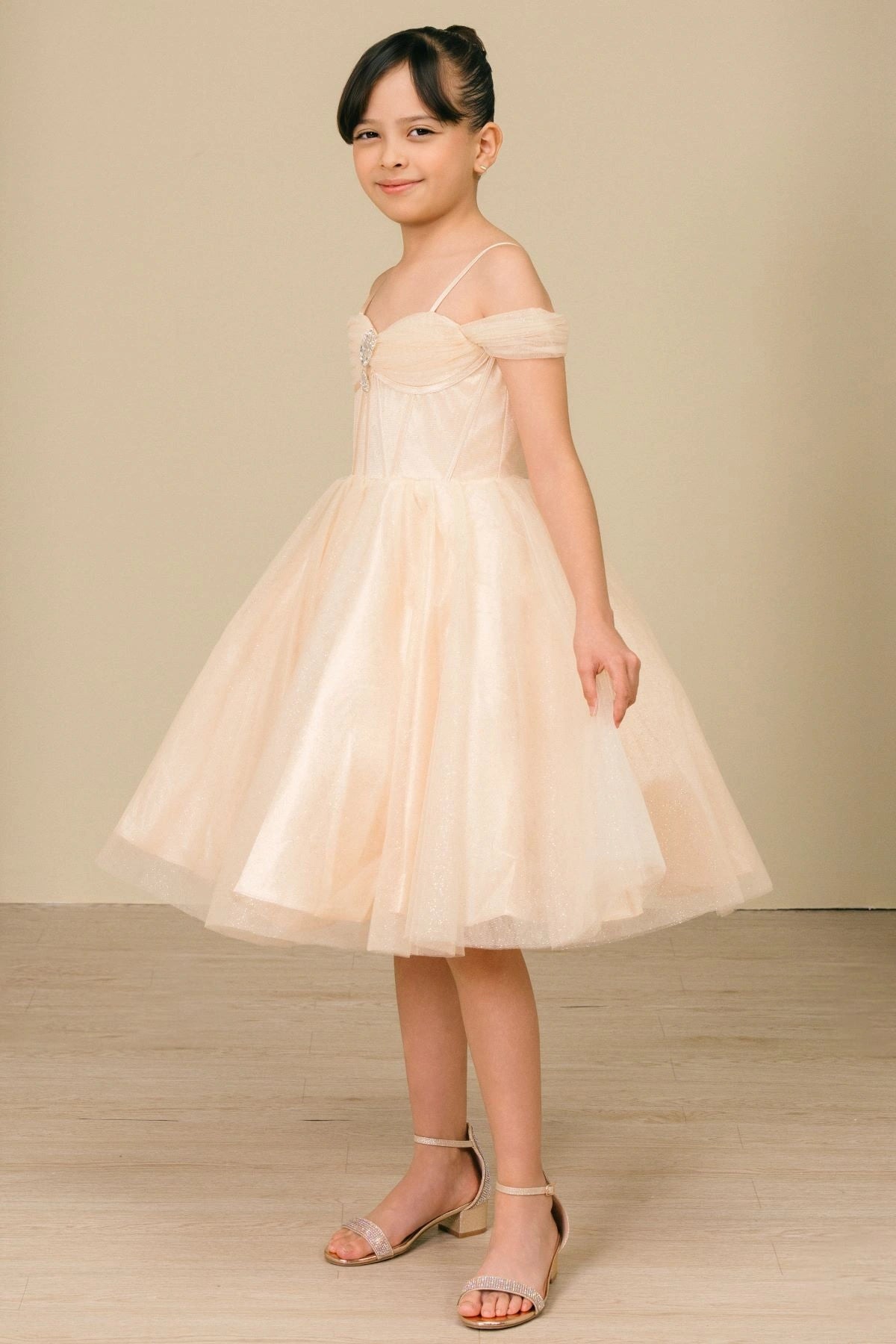 Displayed in a angled view, the Champagne girls formal dress has draped sweetheart bodice and softly layered tulle skirt.