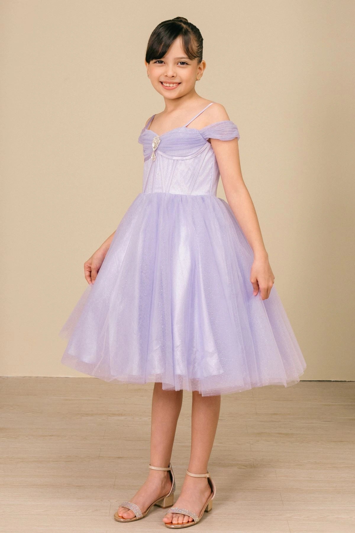 Shown in a front view, the Lilac girls formal dress has off-shoulder draped bodice and full tulle skirt.