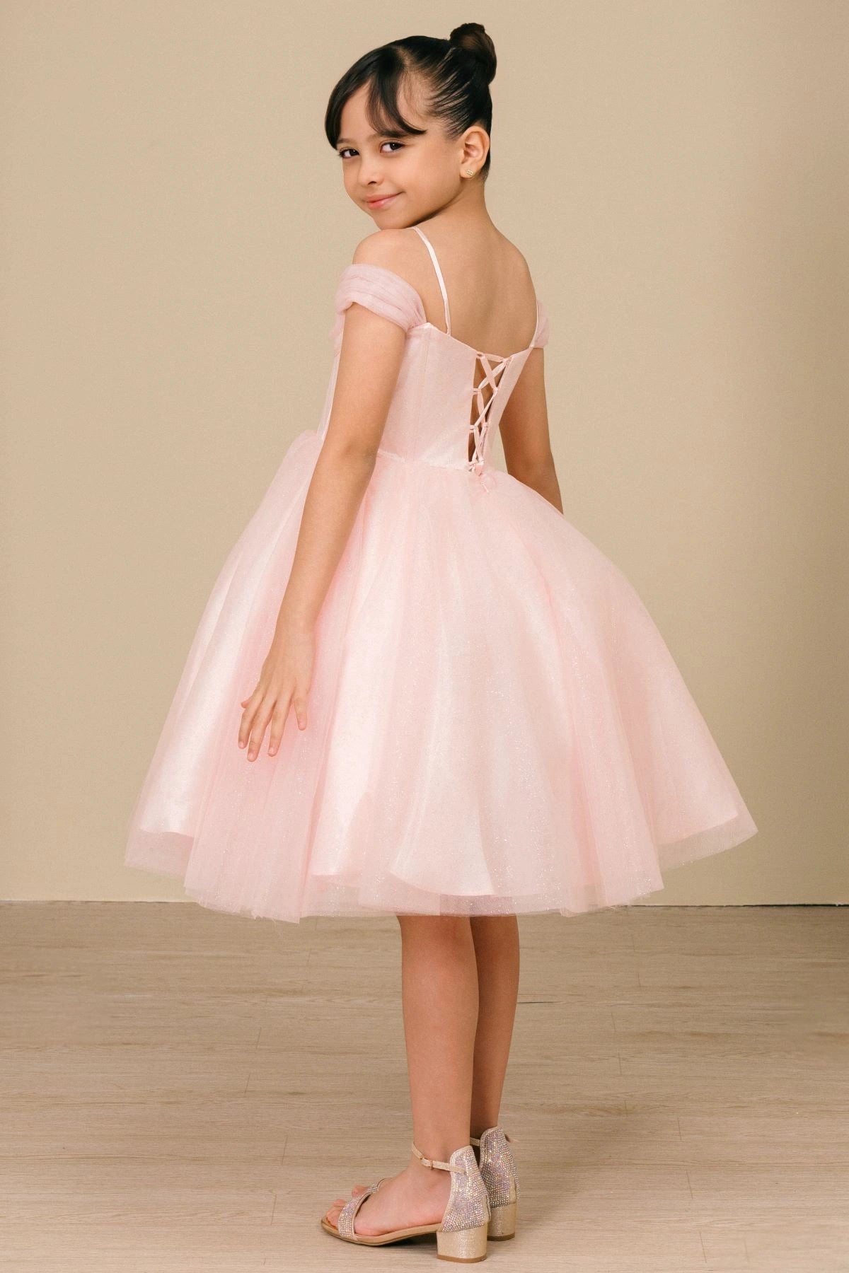 Displayed in a back view, the Pink girls formal dress has lace-up back and thin straps over a full tulle skirt.
