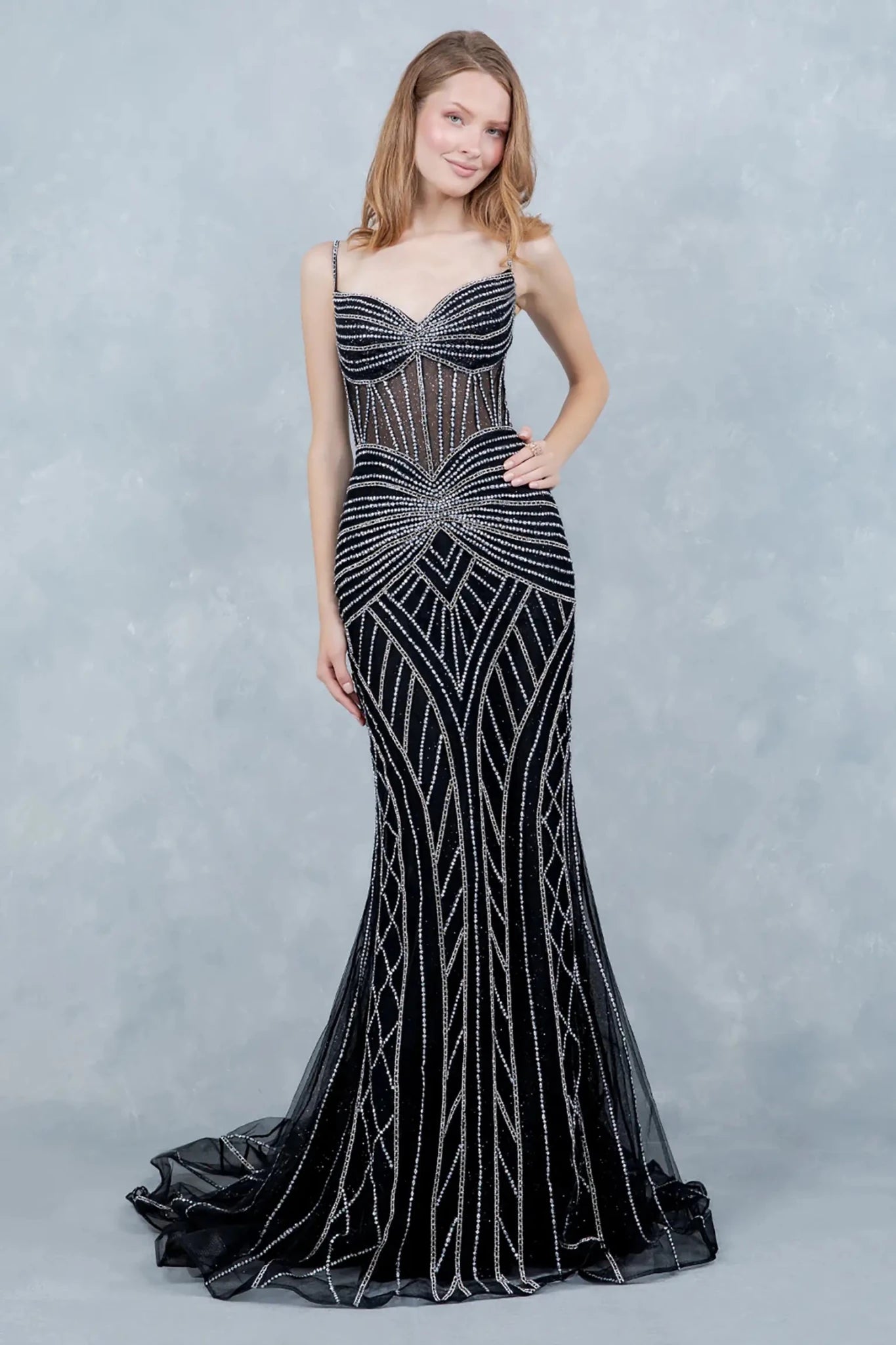 A full-length view of a woman wearing black mermaid dress styled with a lace-up corset and tulle flare.