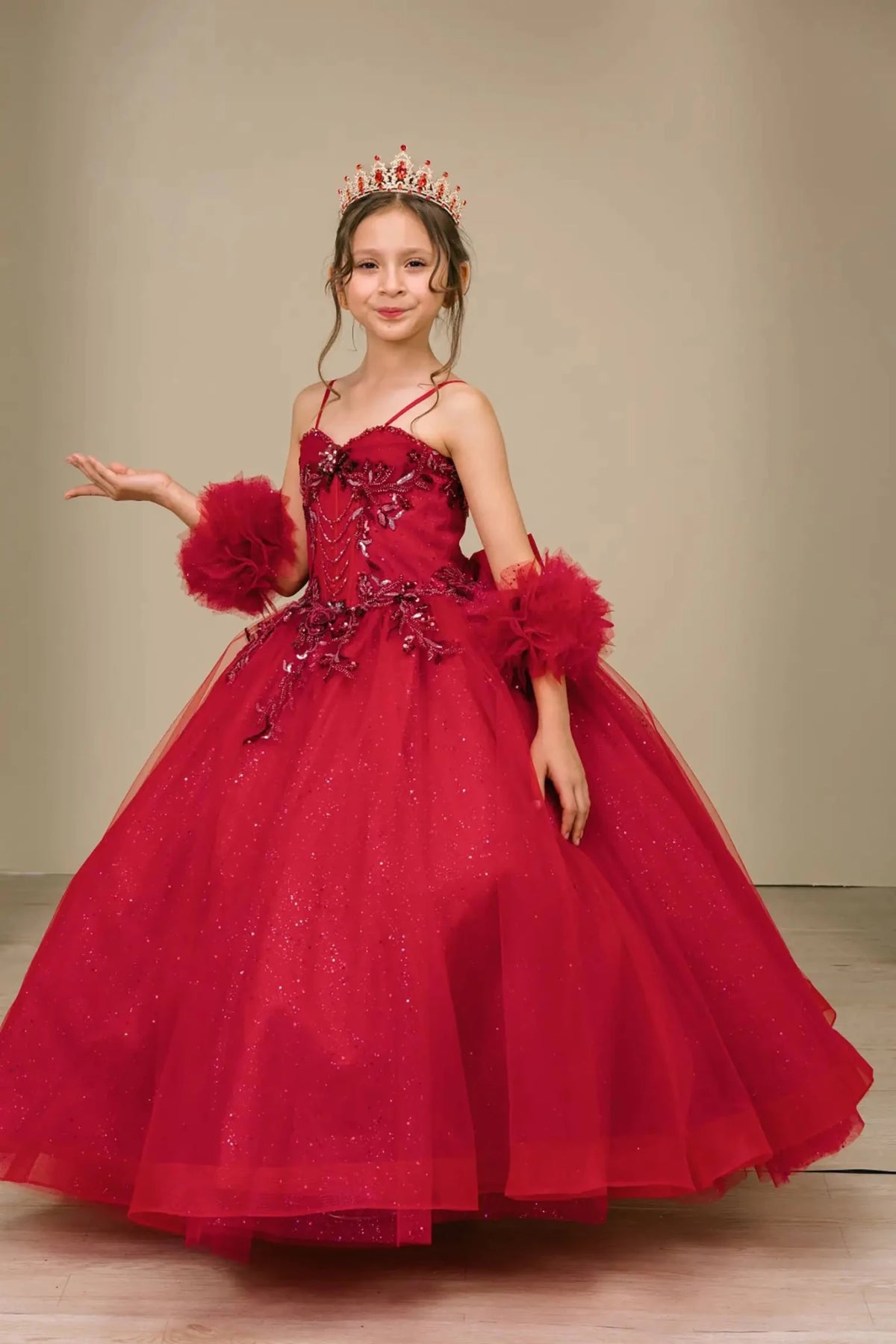 Front view of burgundy mini quinceañera mini quince dress with beaded bodice, floral appliqué, draped details, sparkling tulle skirt, and matching tulle arm cuffs.