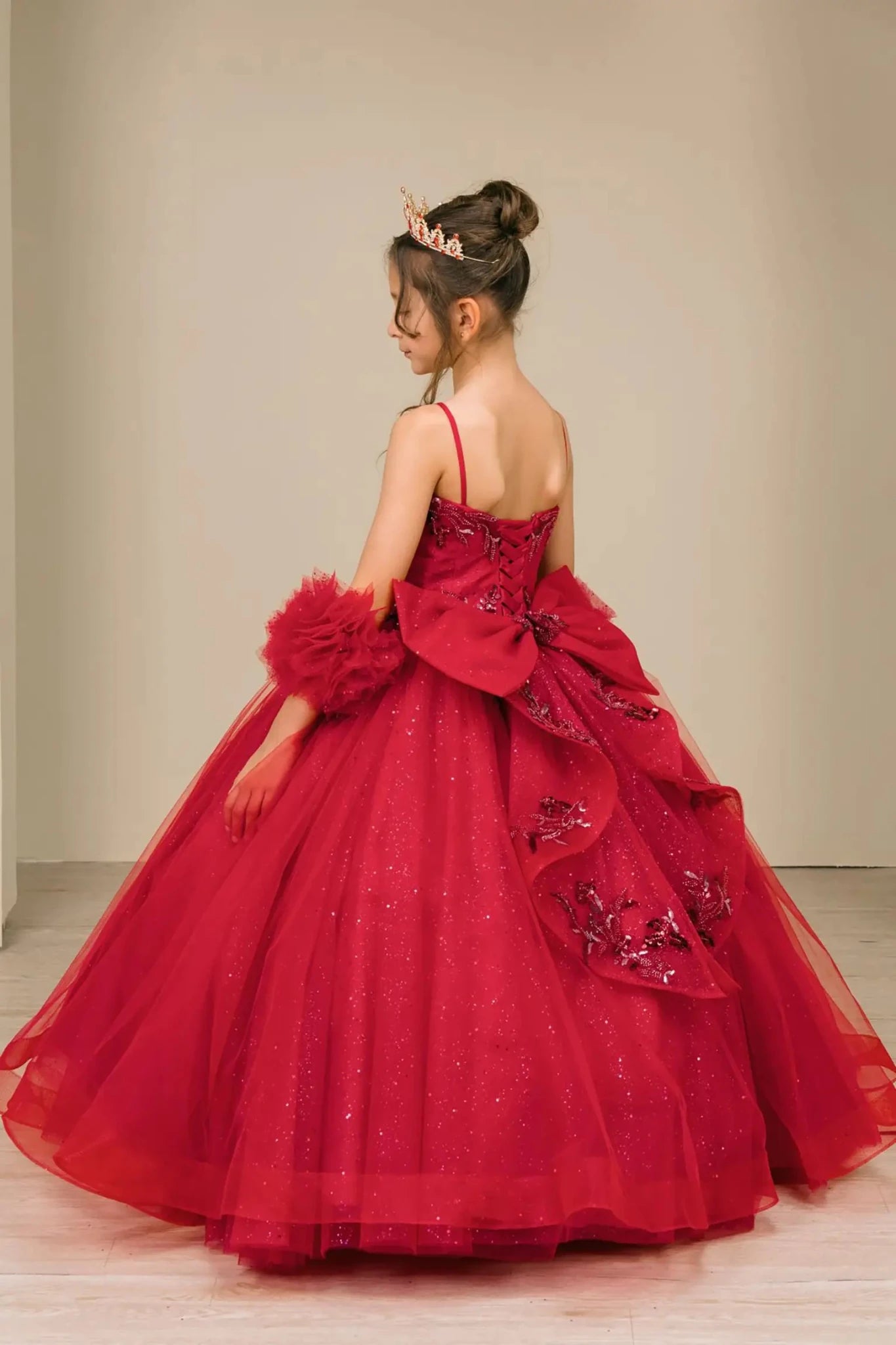 Side view of burgundy mini quinceañera mini quince dress with beaded floral bodice, draped details, sparkling tulle skirt, and layered silhouette.