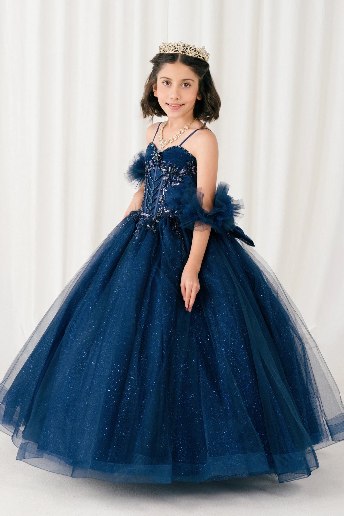 Displayed in a angled view, the Navy mini quince dress has beaded bodice and sheer puff sleeves above a full ball skirt.