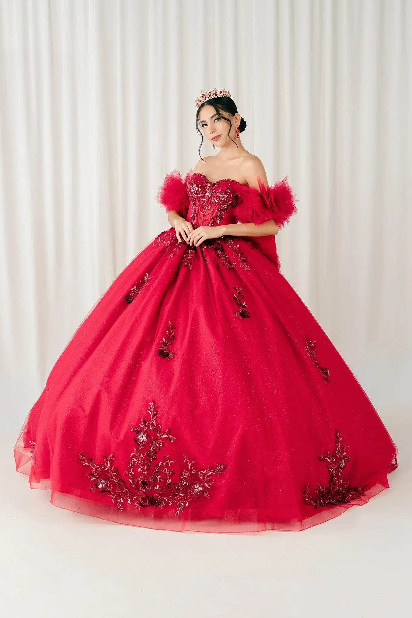 Front view – Red off-shoulder quinceañera ball gown with embellished corset bodice, feathered sleeves, and full glitter tulle skirt.