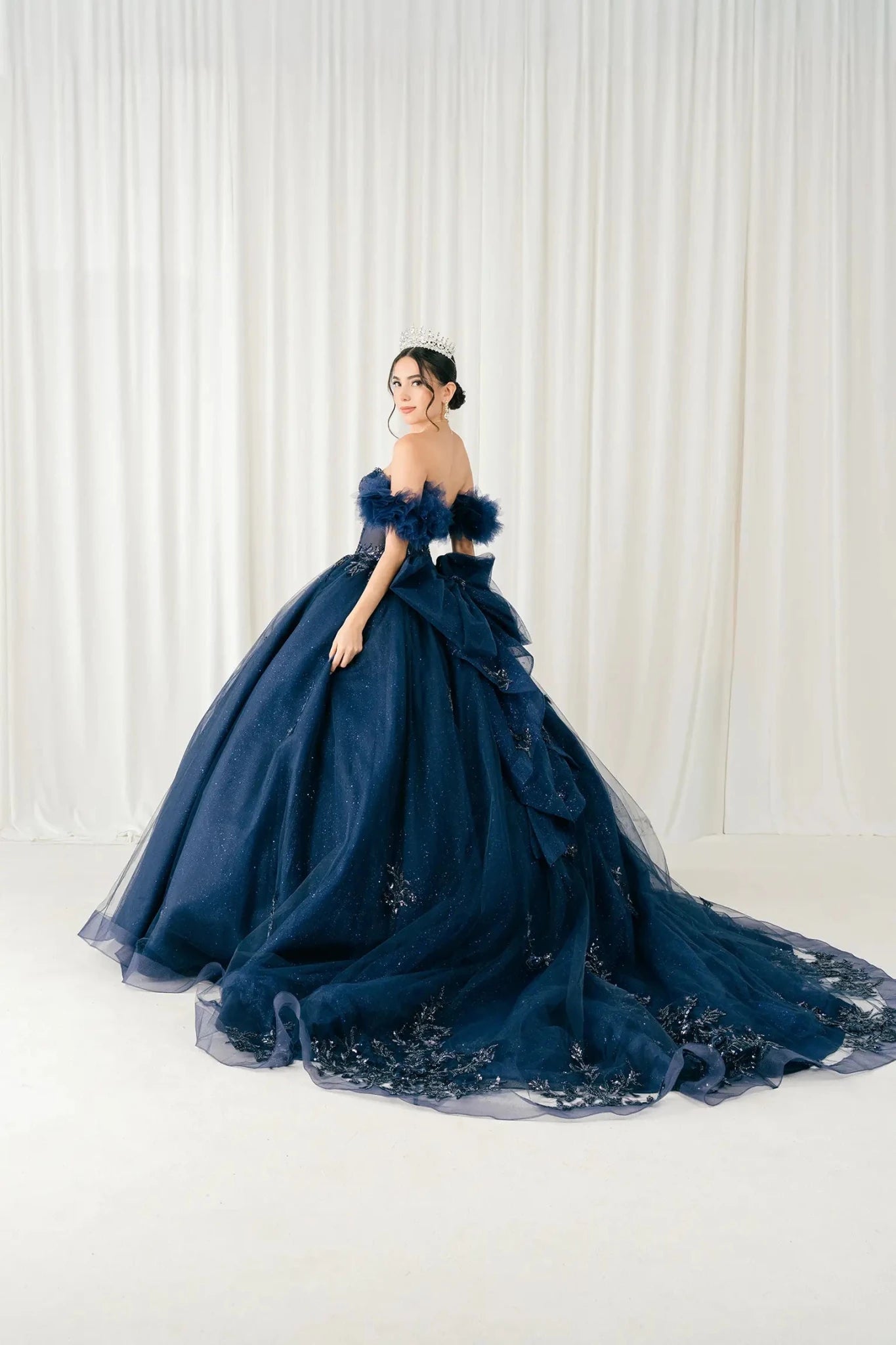 Front full-length view of navy blue off-shoulder ball gown with glitter tulle skirt and embroidered hem