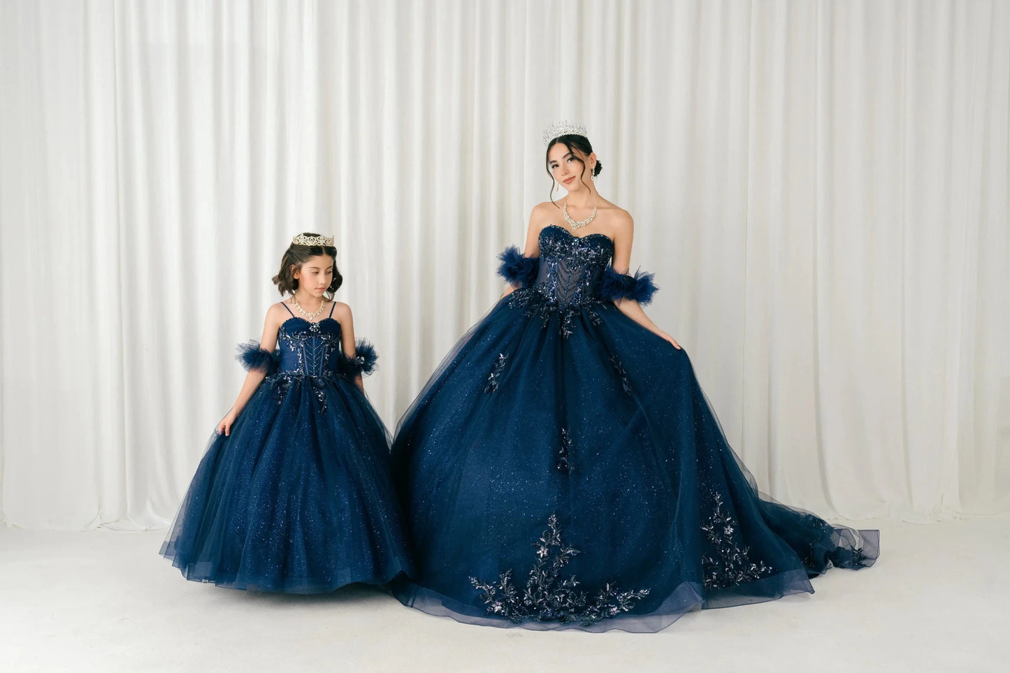 Front full-length comparison view of navy blue mother and daughter matching ball gowns
