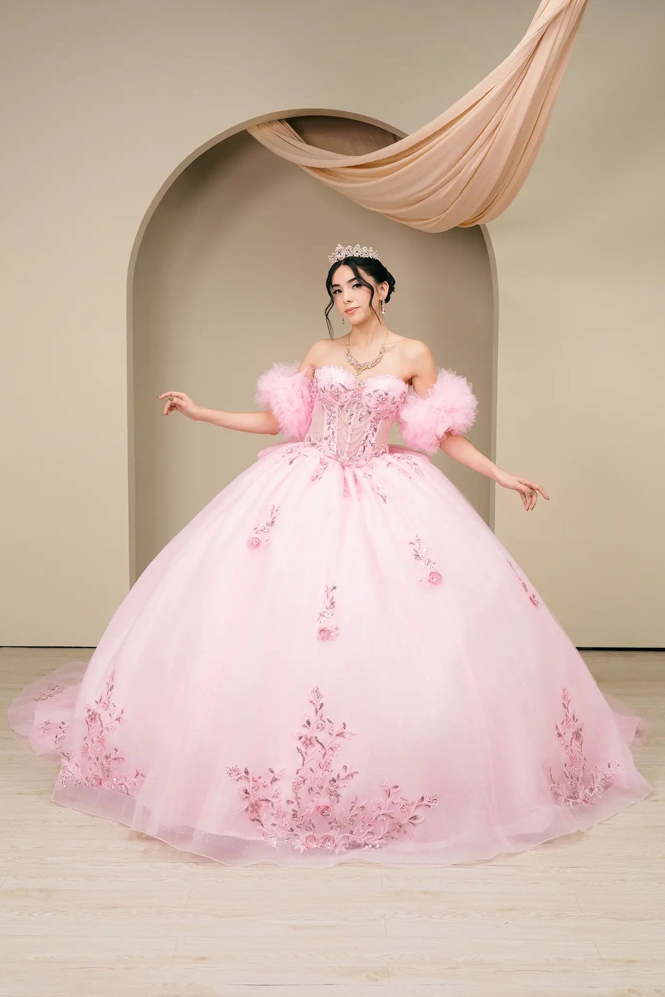 Full front view:
Soft pink quinceañera ball gown with off-shoulder tulle sleeves, embellished corset bodice, and full glitter tulle skirt shown from the front.