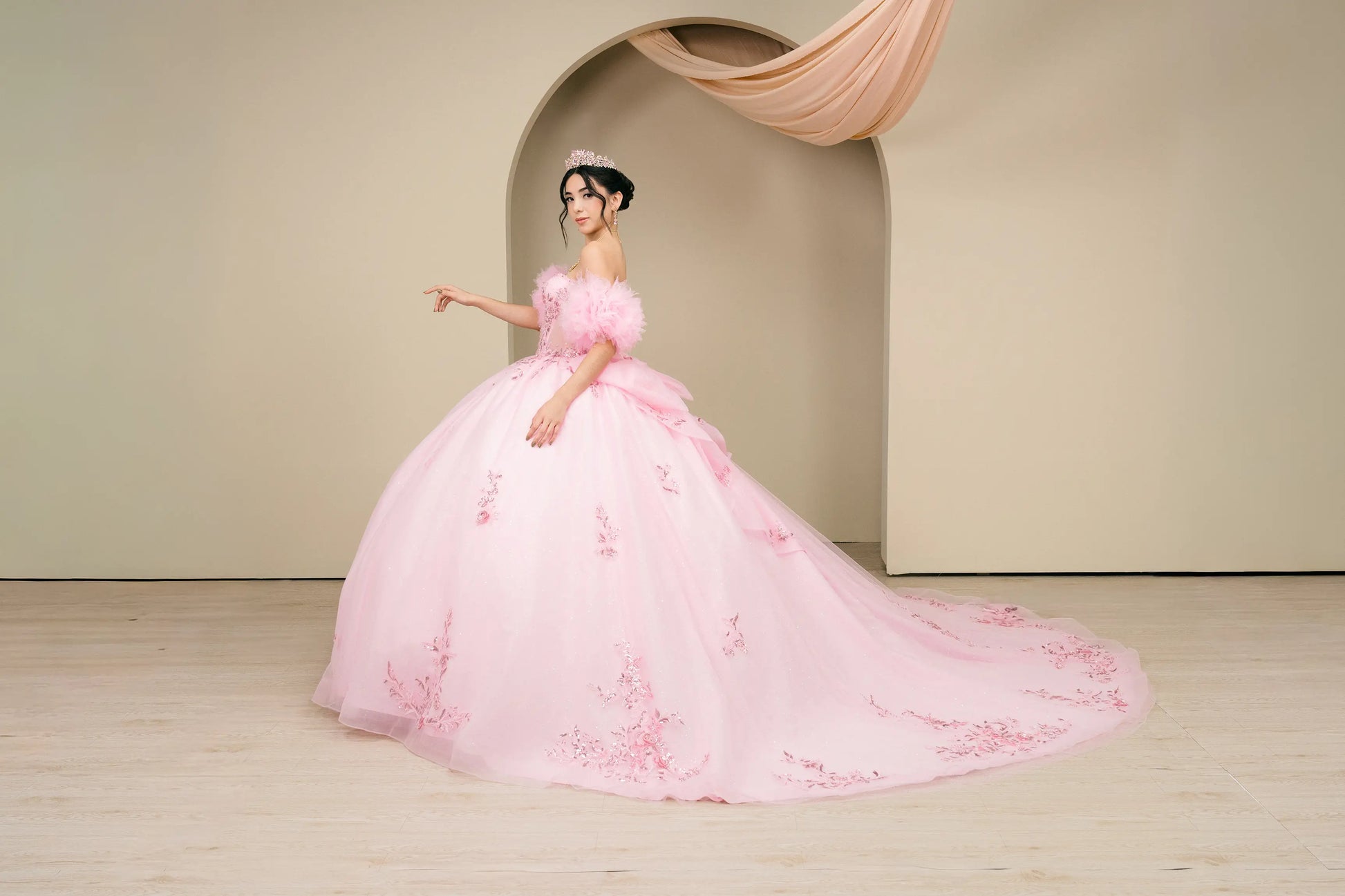 Front full-length view of a pink off-shoulder quinceañera ball gown with floral embroidery and tulle skirt