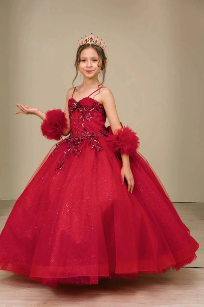 Young girl standing front-facing in burgundy mini quinceañera ball gown with beaded bodice, floral appliqué, draped details, sparkling tulle skirt, and matching tulle arm cuffs