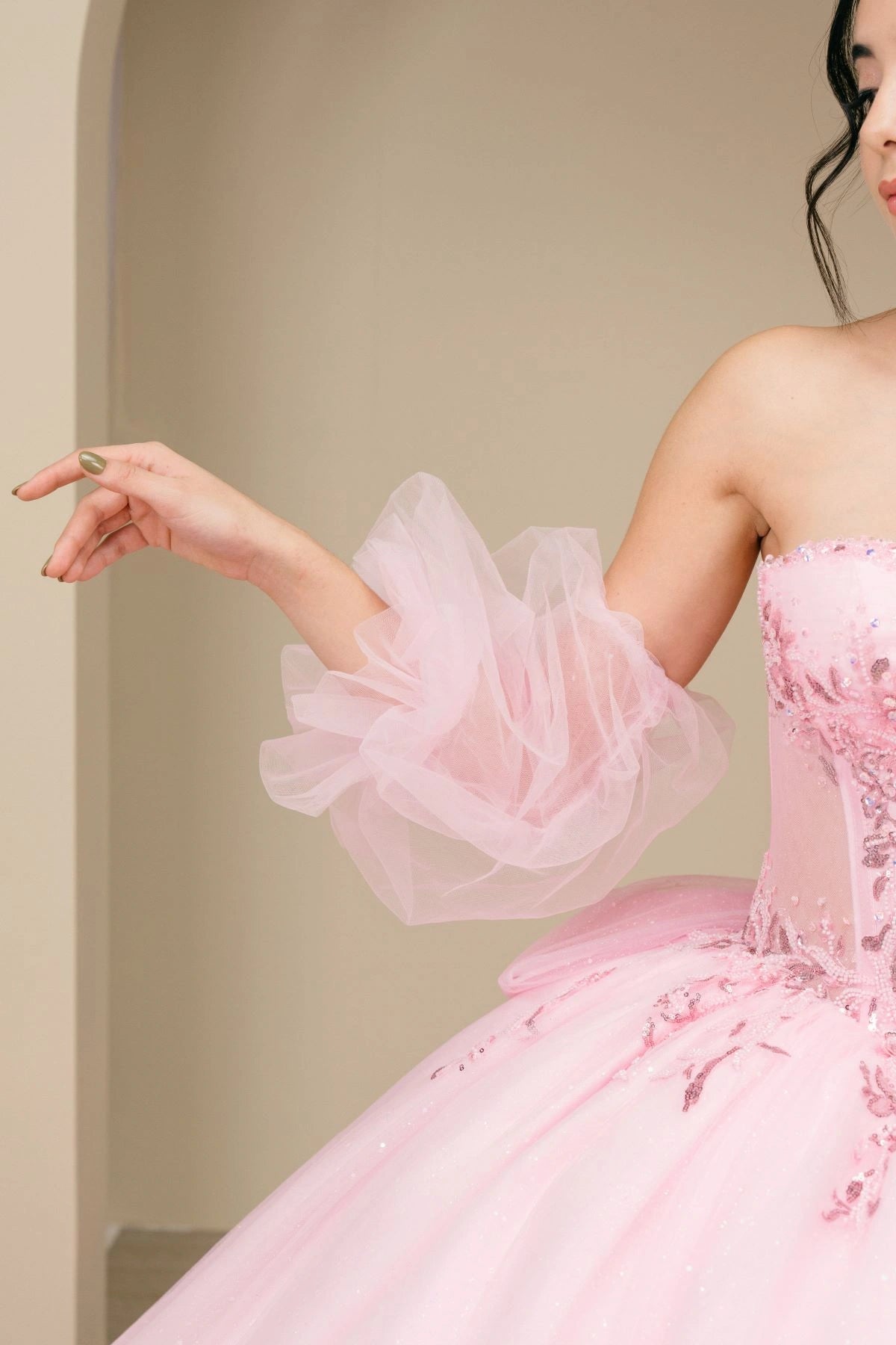 Displayed in a bodice detail, the Pink quinceañera dress has sheer puff sleeve with layered ruffle trim.
