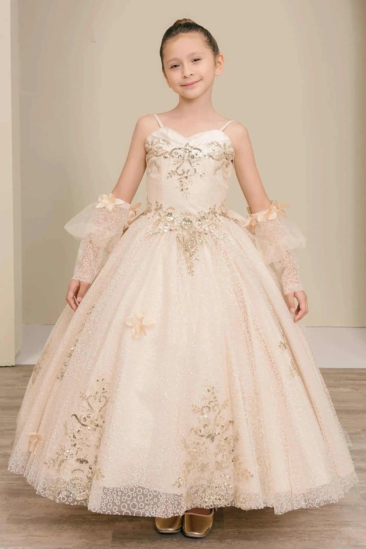 Front full-length view of Champagne mini quince mini quince dress with glitter floral embroidered bodice, full skirt, lace up back, oversized bow, and sheer lace gloves.