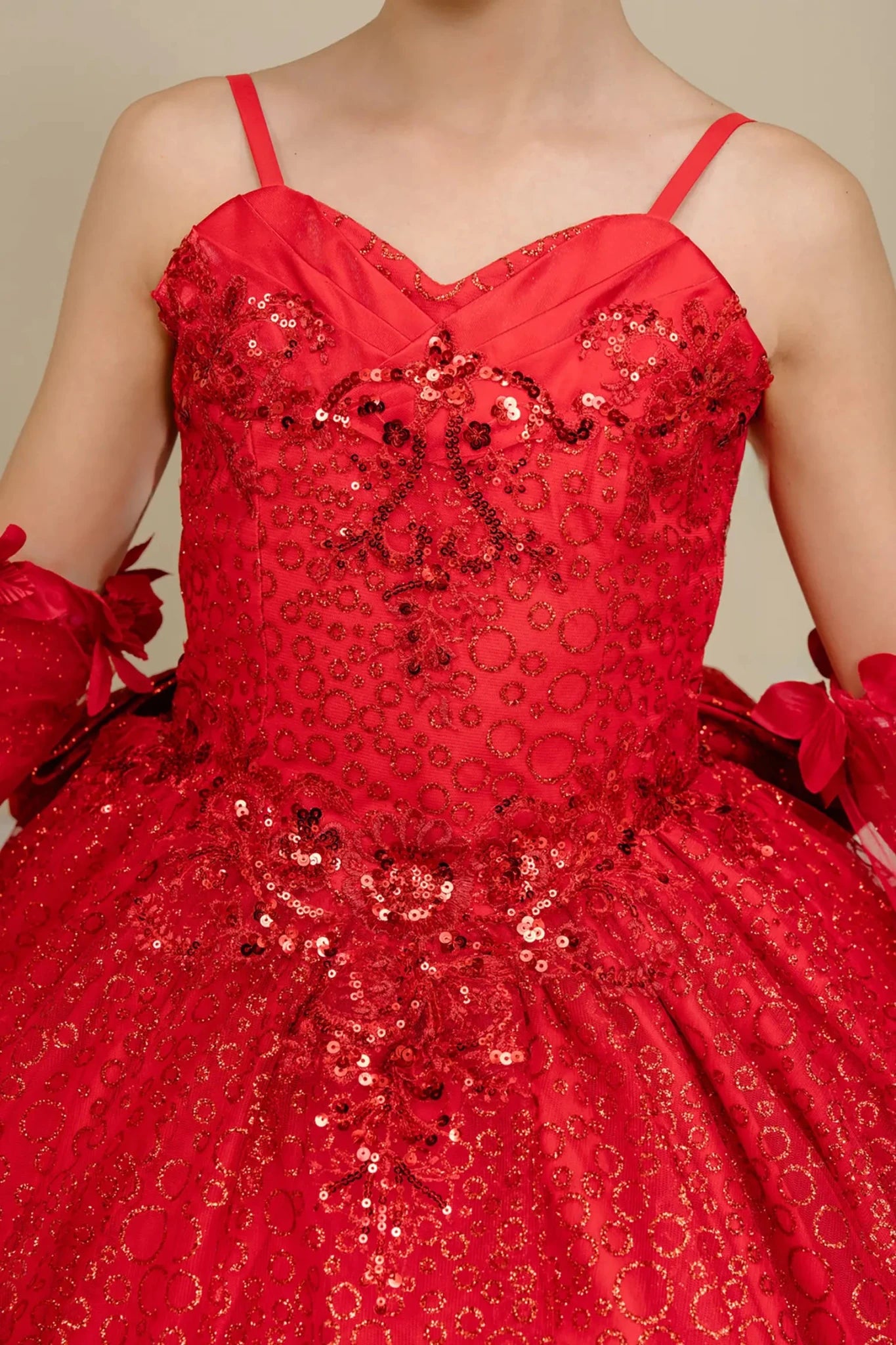 Bodice front close-up of a red kids quinceañera dress with floral embroidery, sequins, and lace-up corset detail.